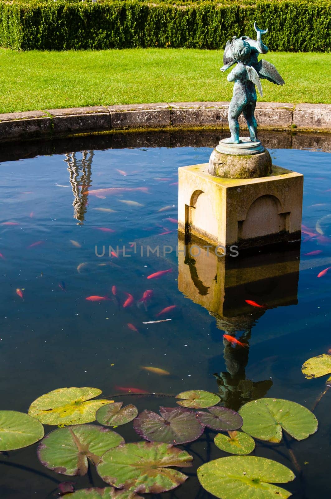 English Landscape garden in Summertime with fishpond and statue