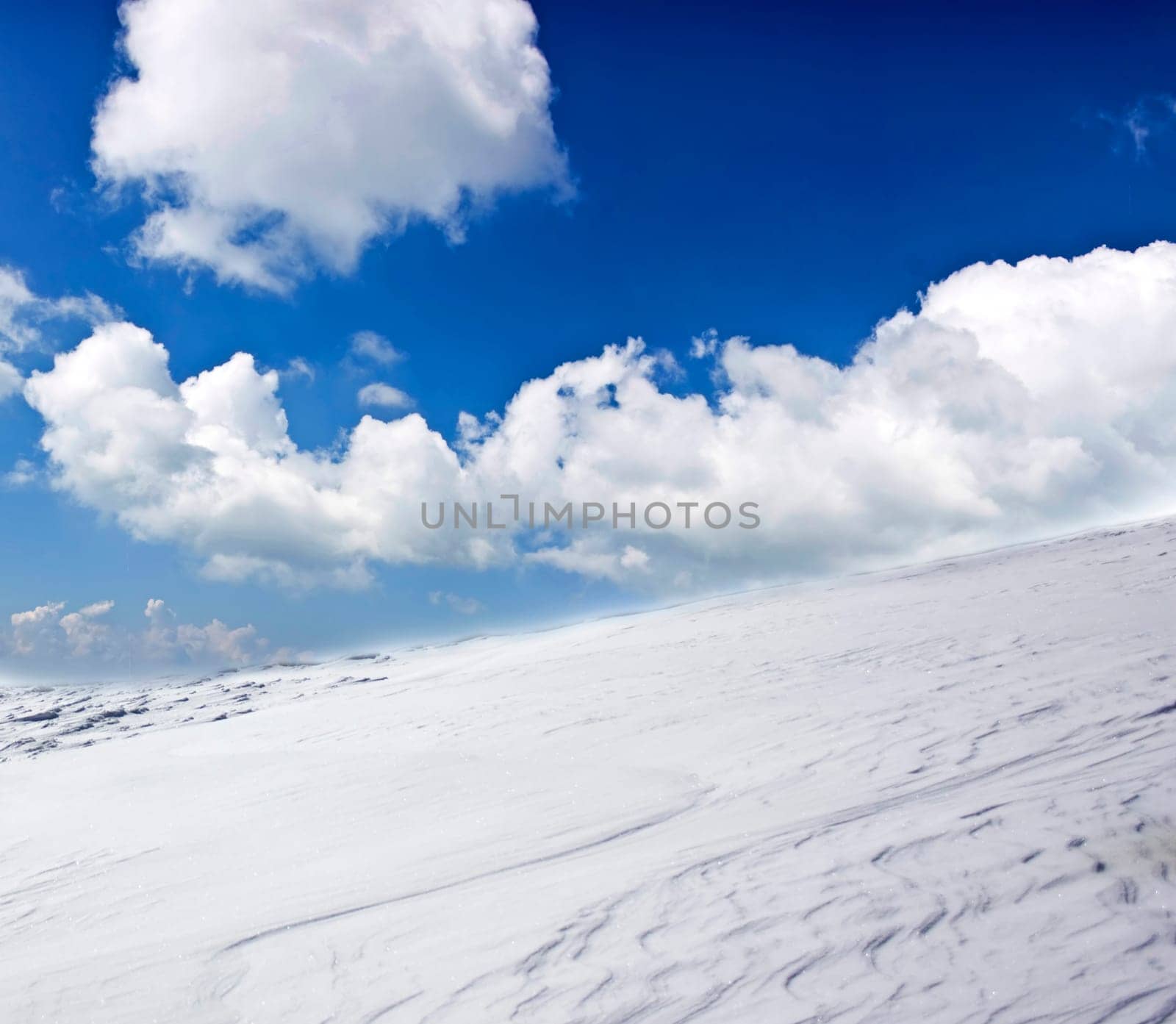 Winter landscape with snow covered hill and cloudy blue sky