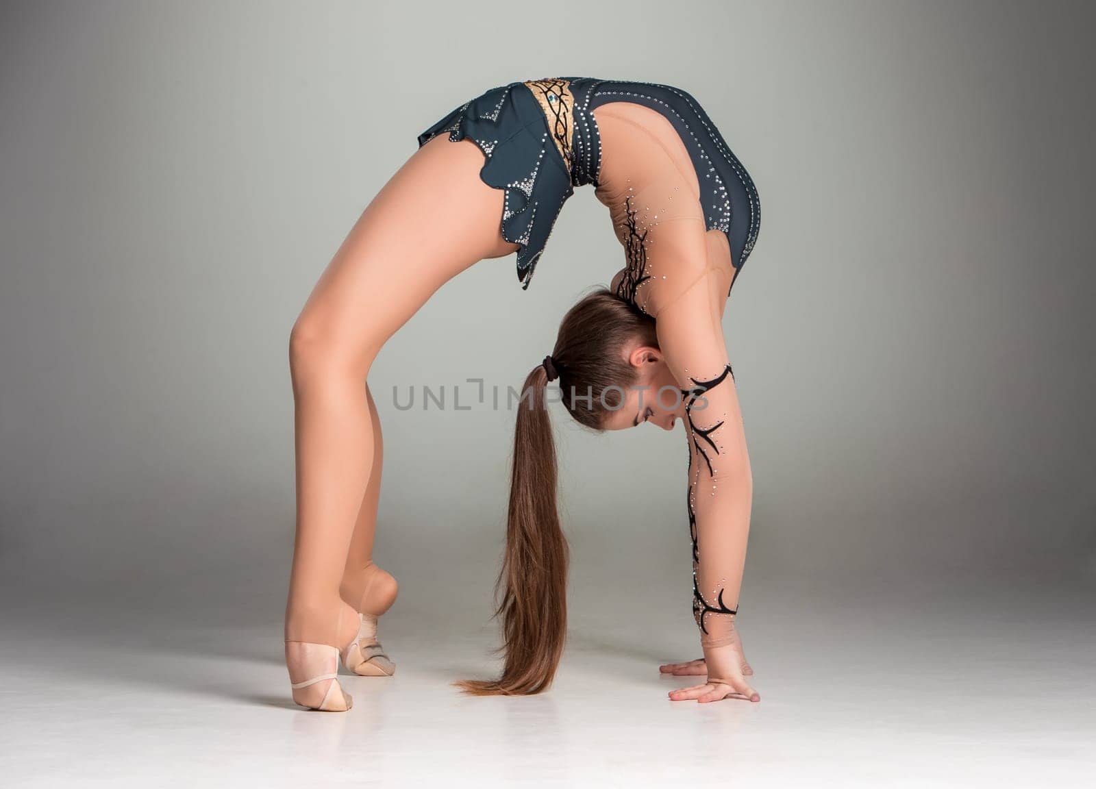 teenager doing gymnastics exercises  on a gray background