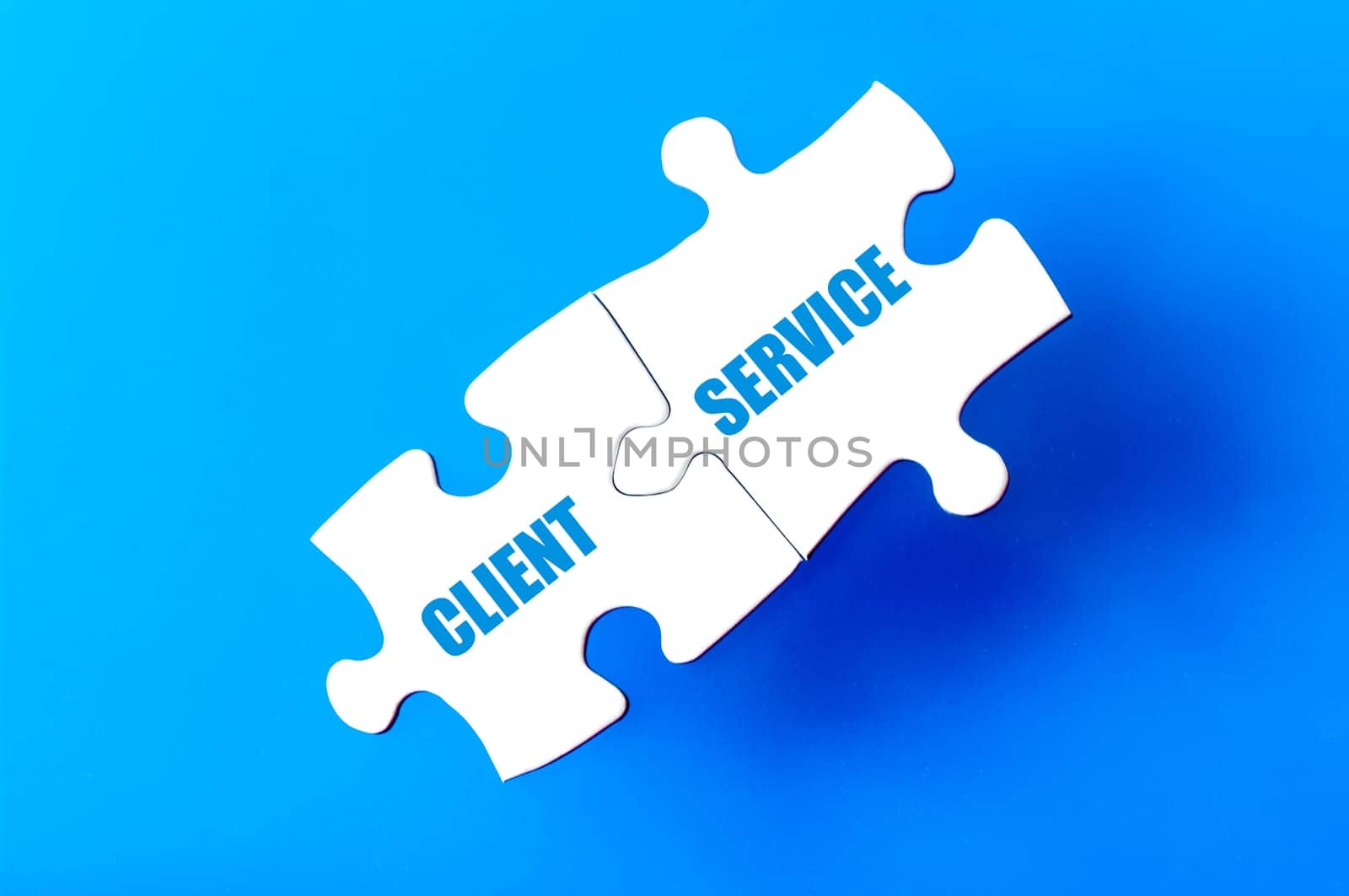 Connected puzzle pieces with words CLIENT and SERVICE  isolated over blue background, with copy space available. Business concept image.