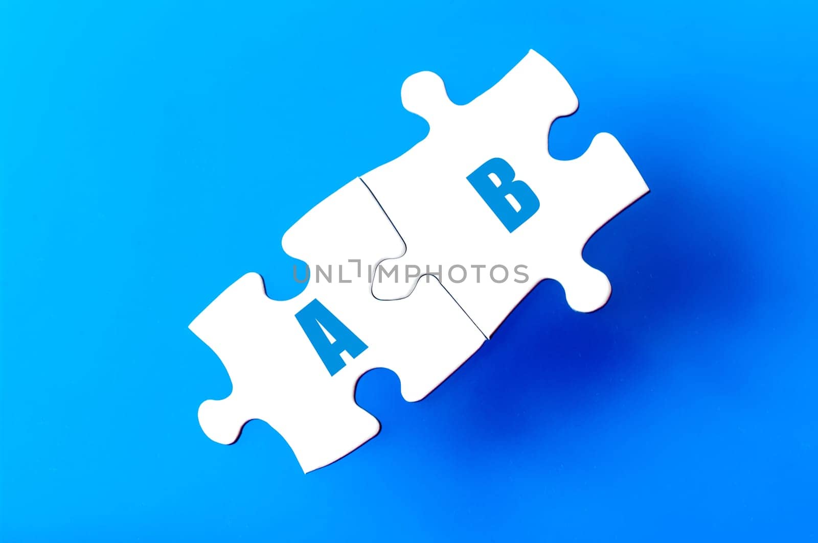 Connected puzzle pieces with letters A and B  isolated over blue background, with copy space available. Business concept image.