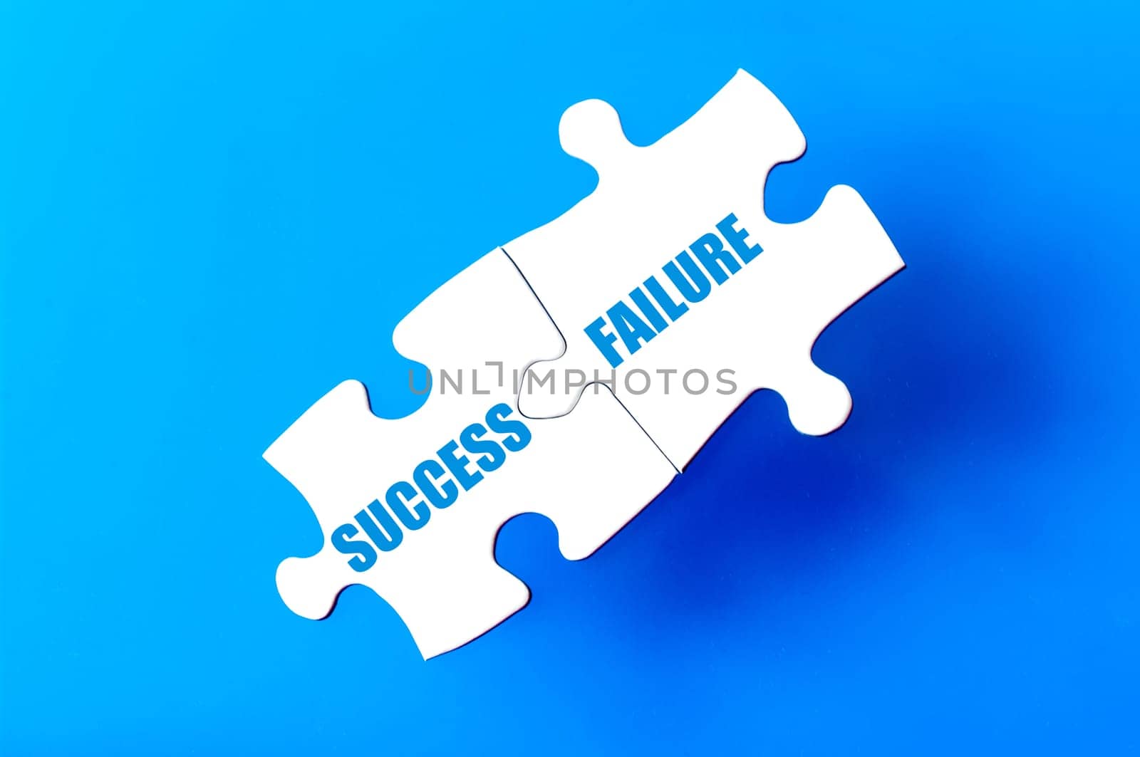 Connected puzzle pieces with words SUCCESS and FAILURE  isolated over blue background, with copy space available. Business concept image.