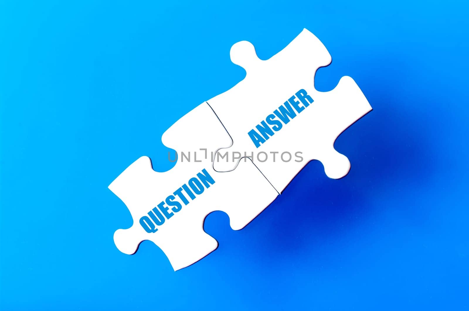 Connected puzzle pieces with words QUESTION and ANSWER  isolated over blue background, with copy space available. Business concept image.