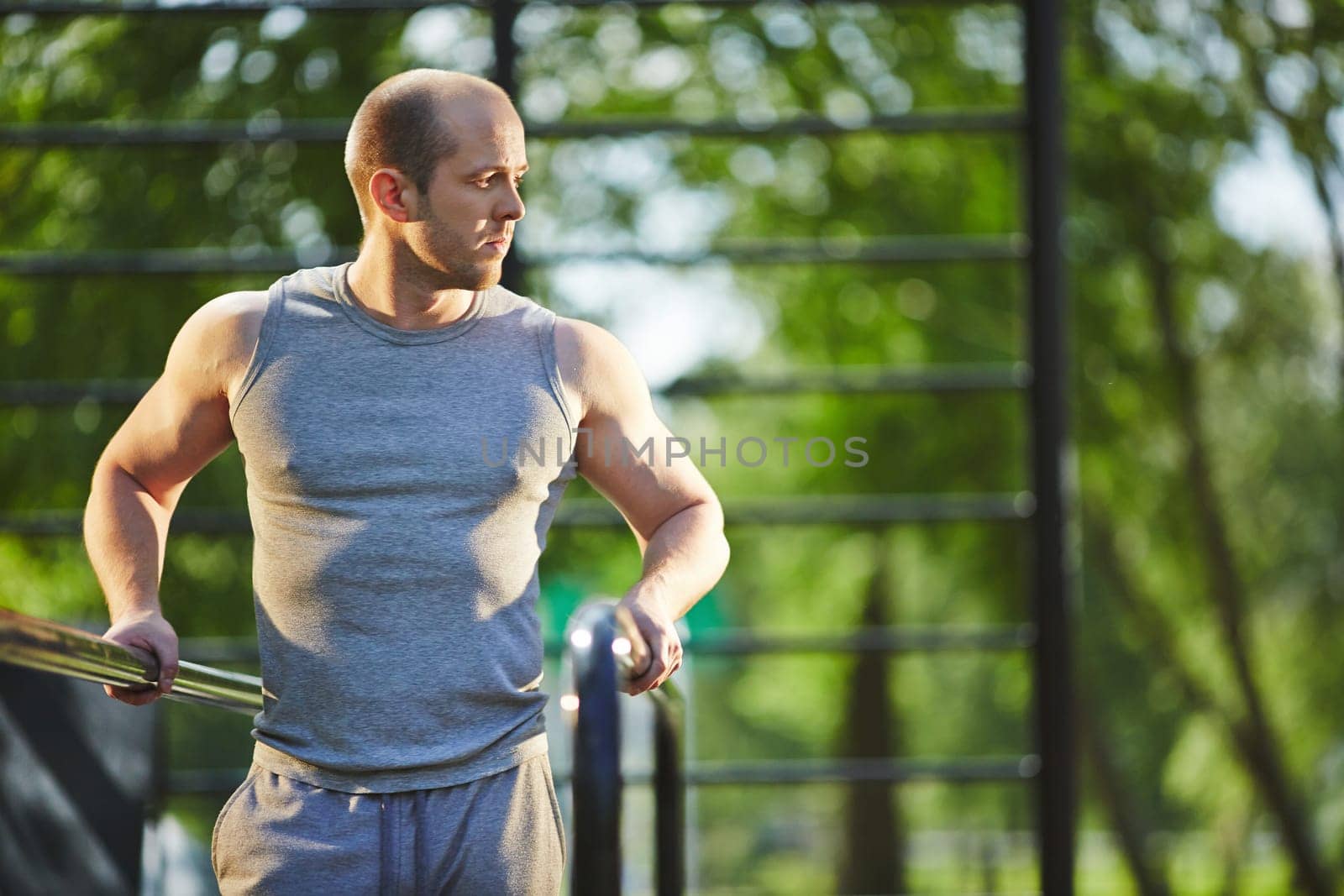 Sporty man in grey vest training in natural environment