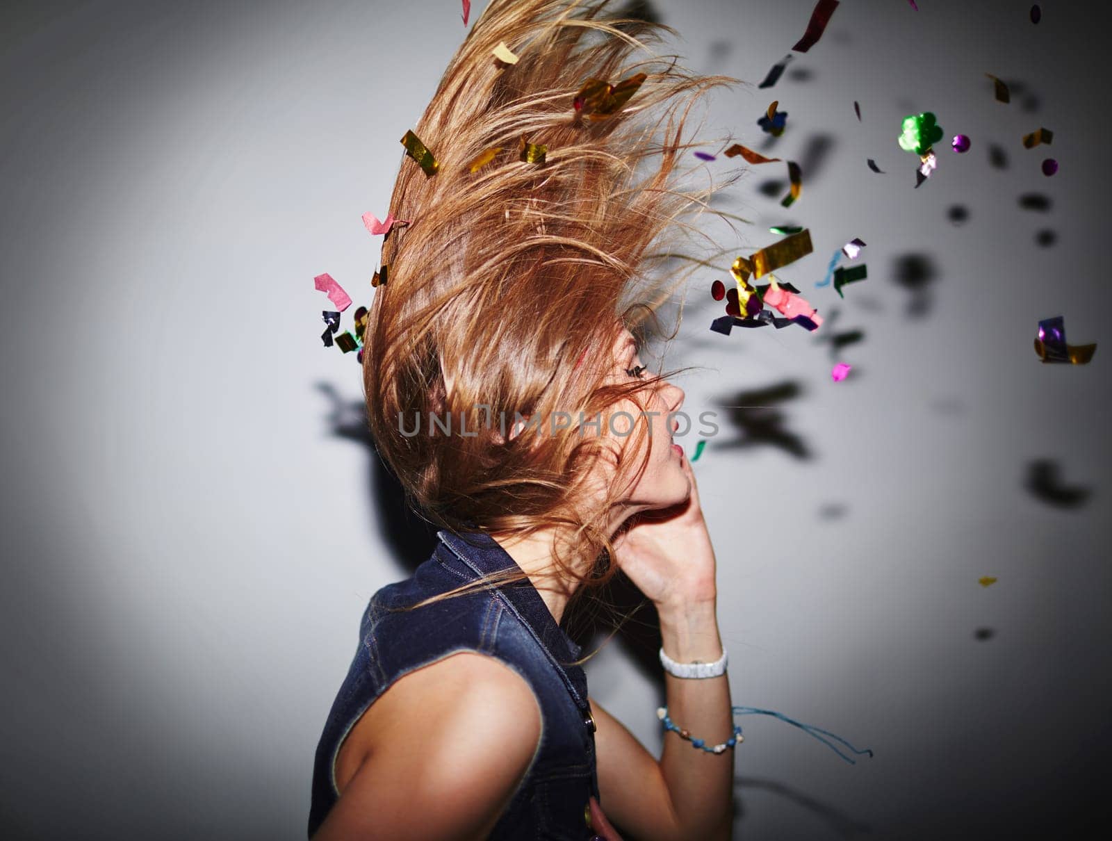 Energetic female dancer with confetti having fun in nightclub