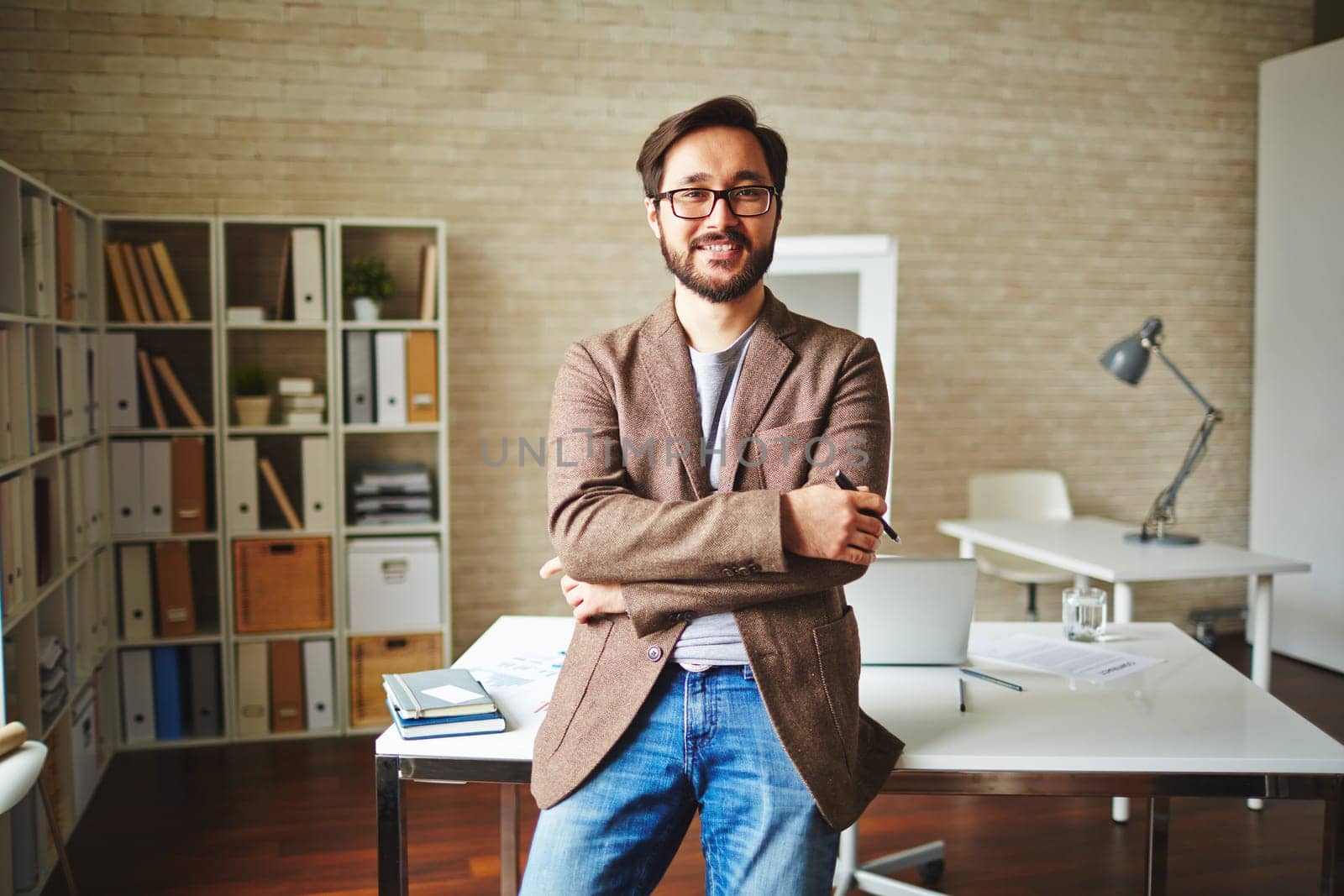 Asian businessman standing by his desk in office