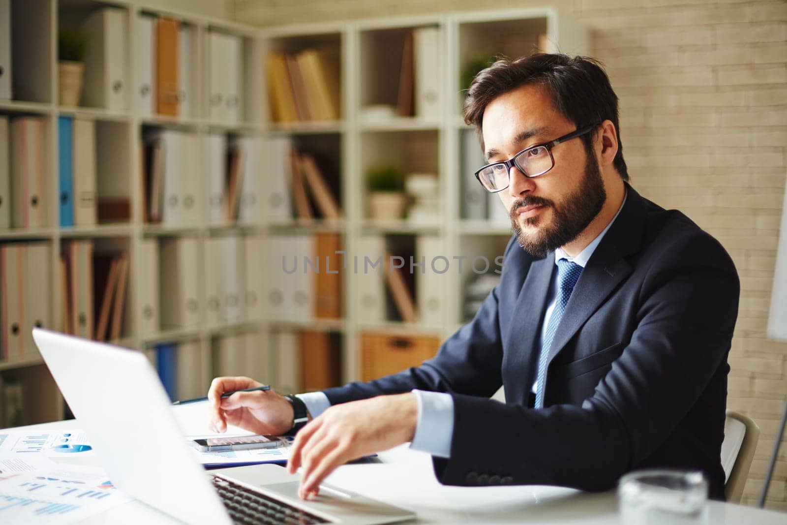 Serious businessman browsing in laptop at workplace