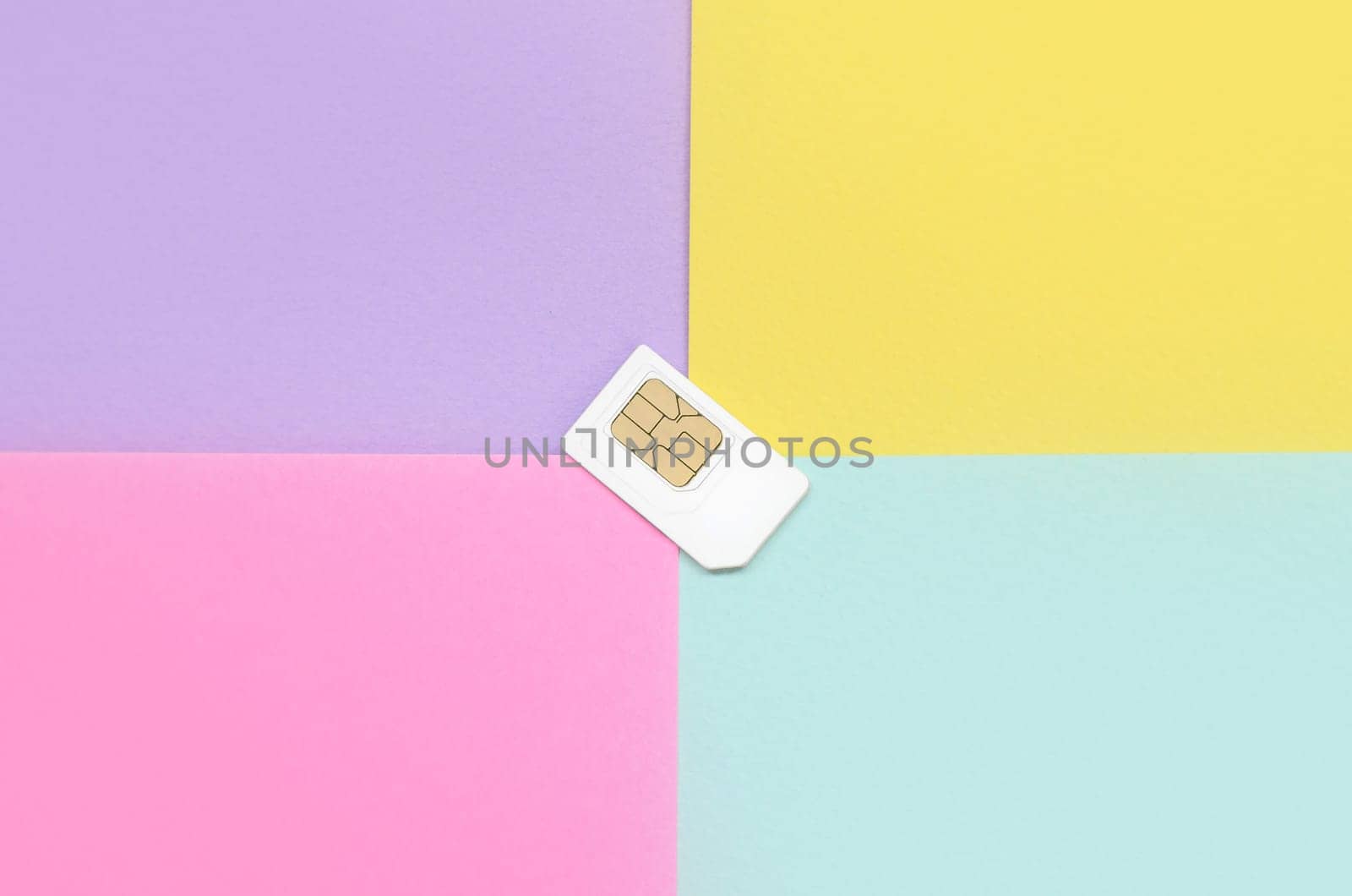 Subscriber identity module. New white SIM card on bright multicolor background. Minimal flat lay top view. Violet, pink, yellow and blue pastel colors