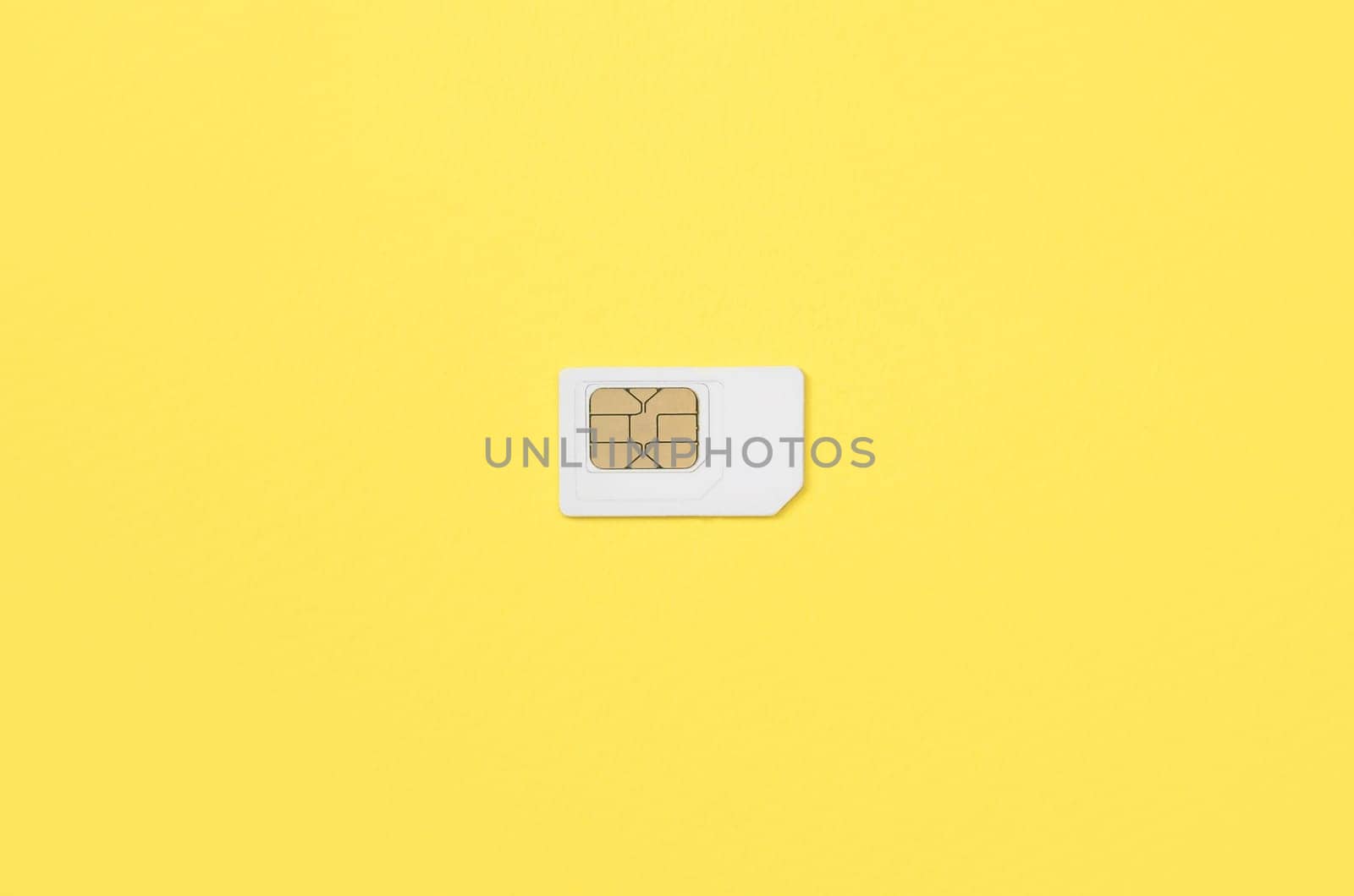 Subscriber identity module. New white SIM card on bright yellow color background. Minimal flat lay top view