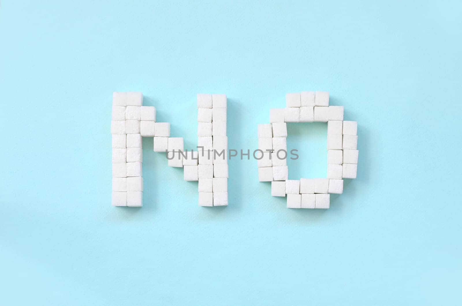 NO Letters of sugar cubes on a pastel blue background. Diabetic concept. Refusing sugar. Flat lay minimal top view
