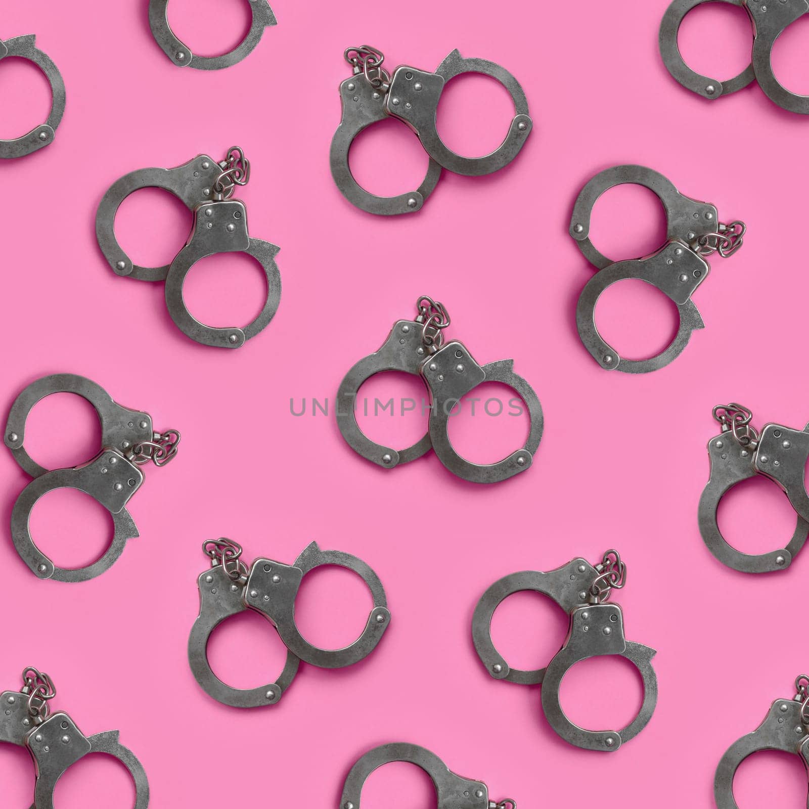 Bdsm sex games concept. Many steel handcuffs lies on pastel pink background. Bondage and Discipline, Domination and Submission, Sadism and Masochism