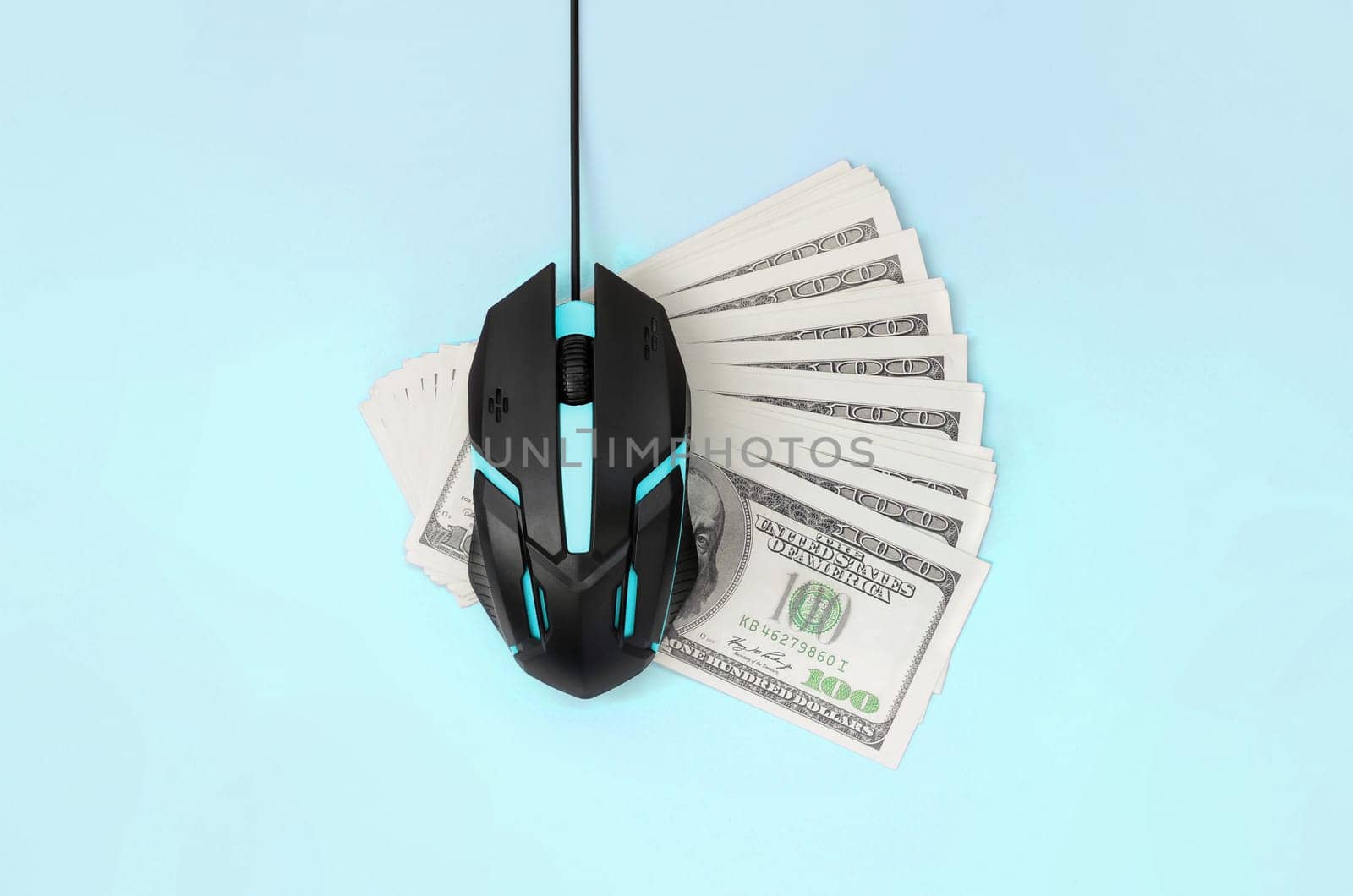 Computer mouse on many dollar bills. Pay per click and autoclicker concept. Earnings on the Internet. Flat lay top view on pastel blue background