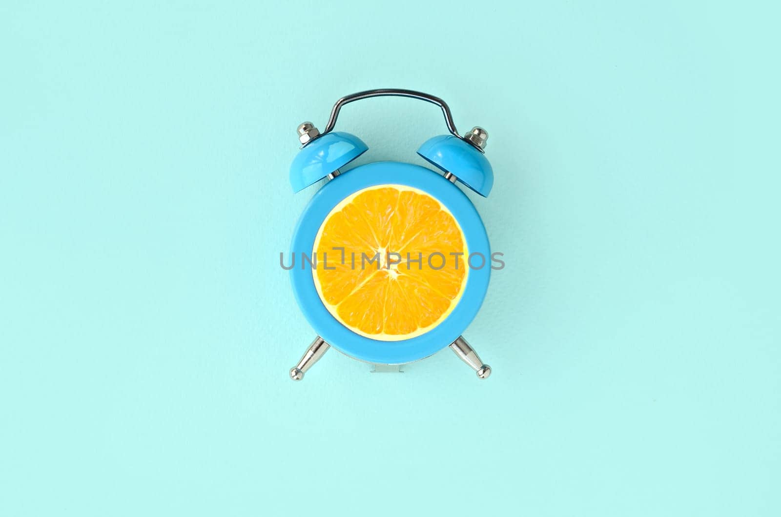 Creative idea fresh orange slice alarm clock on pastel blue background. Minimal business concept. Fruit idea creative to produce work within advertising marketing solutions