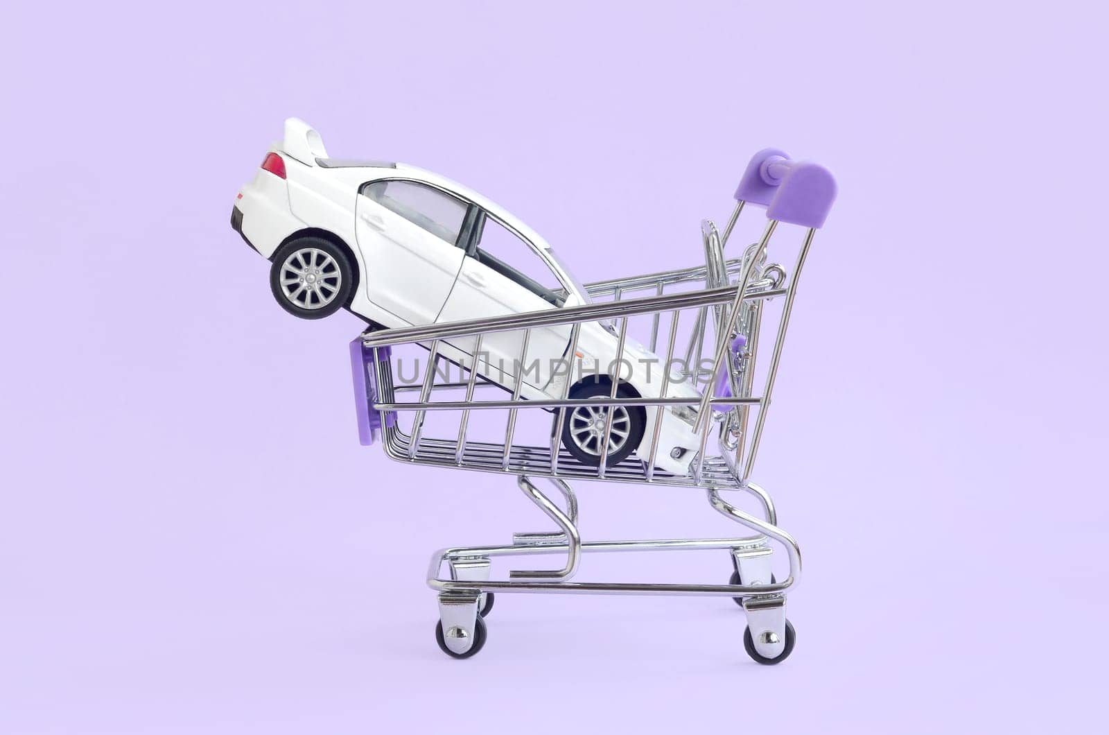 New white toy car in shopping cart as a symbol for car buying and leasing