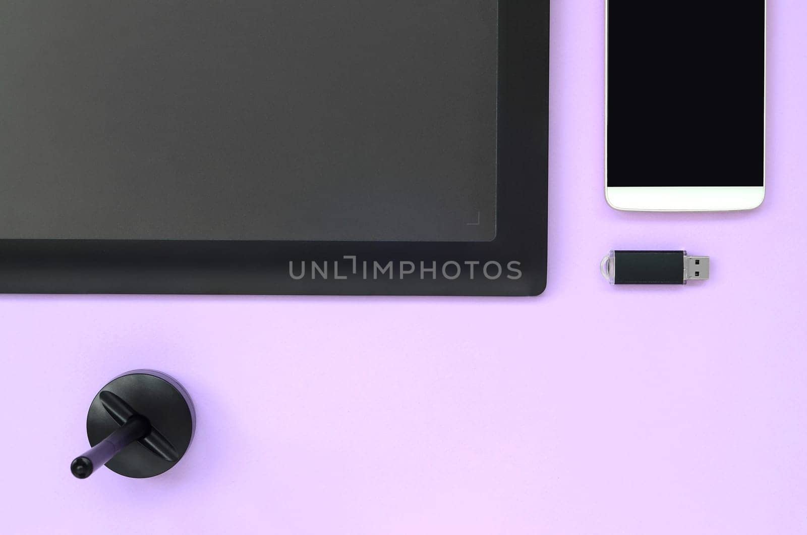 Graphic tablet and pen for illustrators and designers lies with USB memory card and smartphone on pastel violet background. Flat lay minimalism. Top view