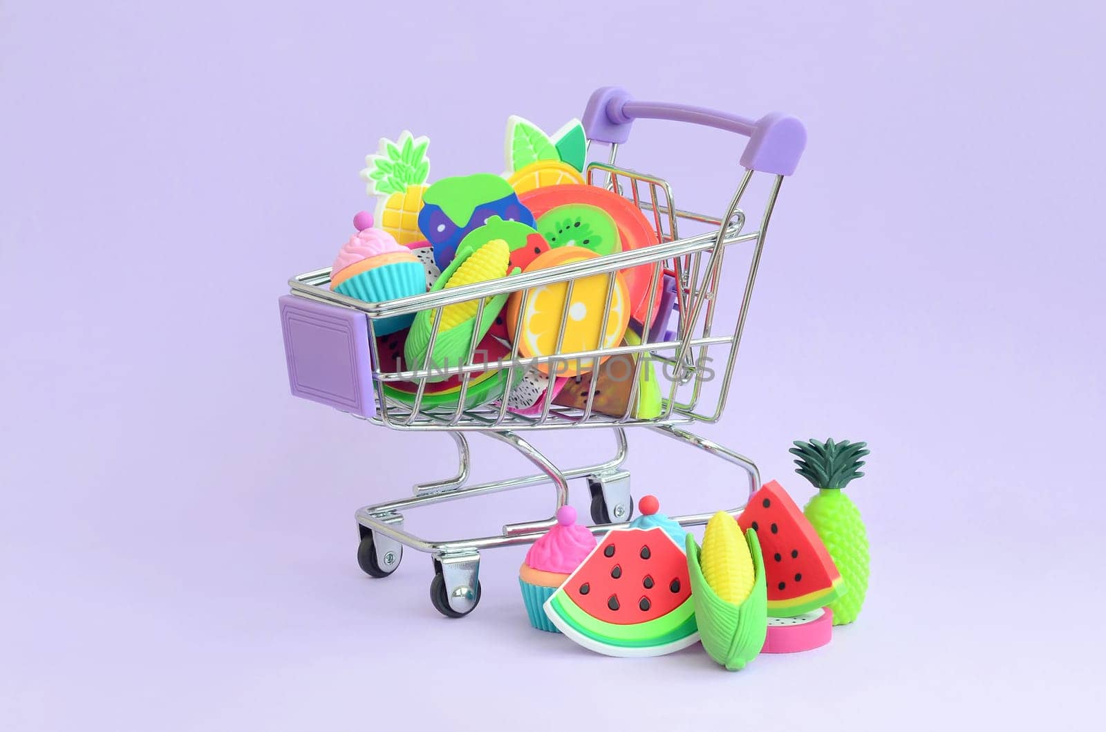 Shopping cart is filled to the top with fresh fruits on a purple background. The concept of buying food and fruit online. Diet food
