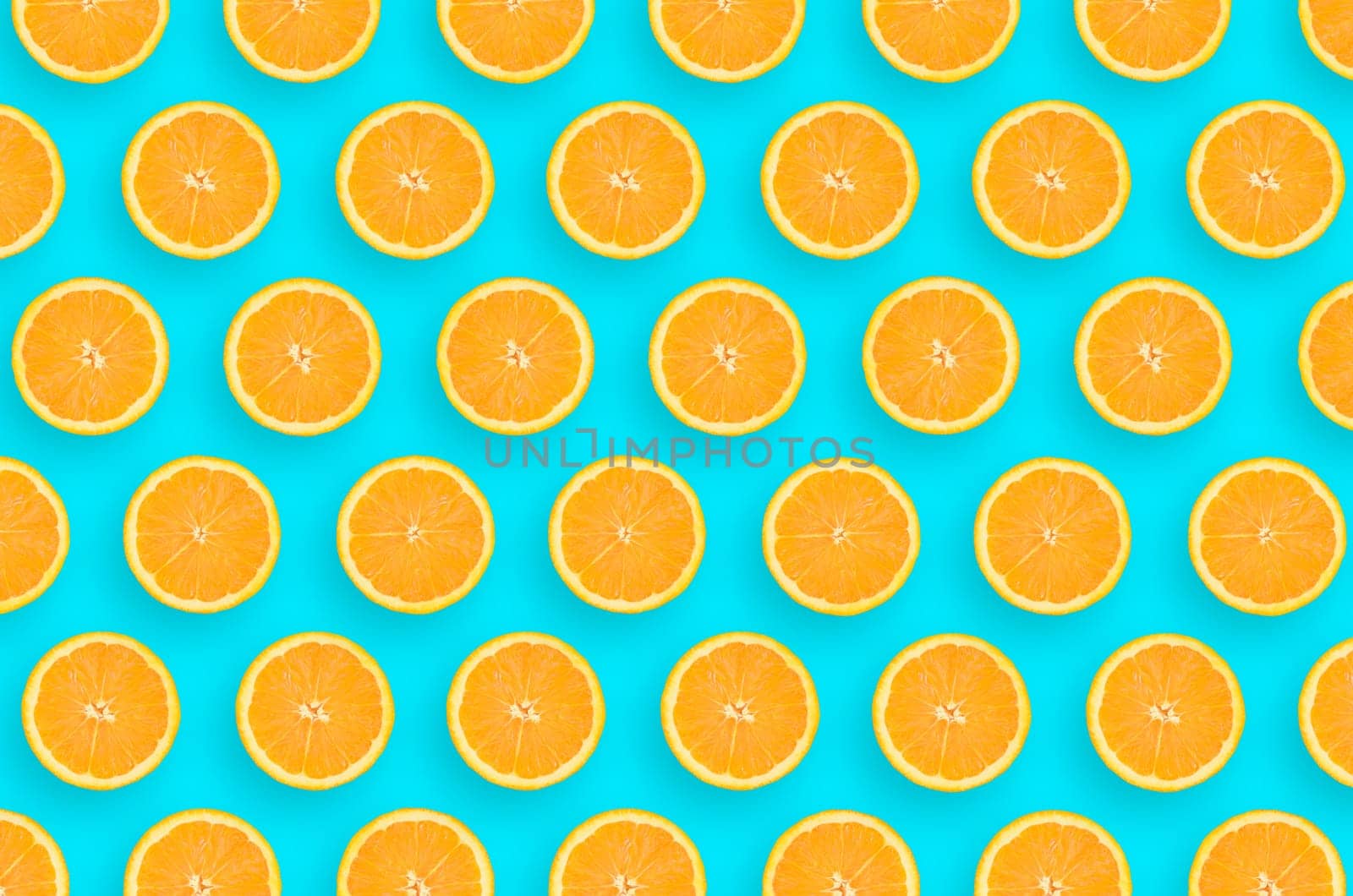 Top view of a orange fruit slices on bright blue background. A saturated citrus pattern. Minimalistic flat lay