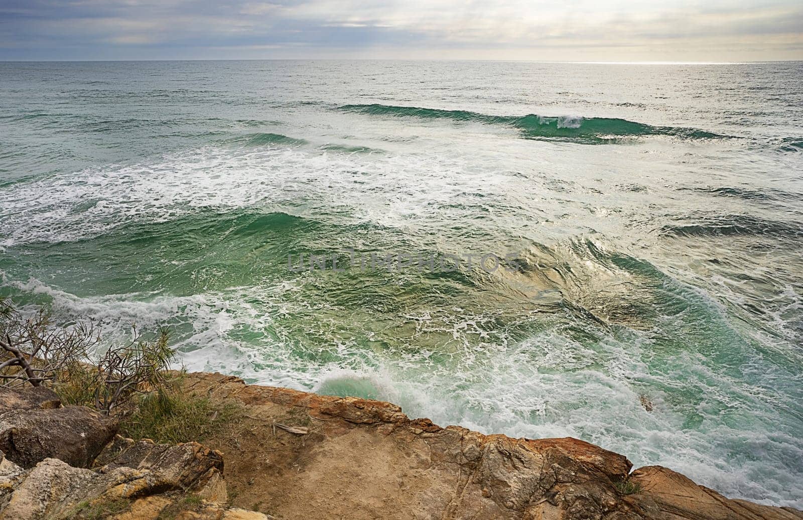 Churning, turbulent water breaking over rocks at high tide along a rocky coastline on the Sunshine coast, Queensland.