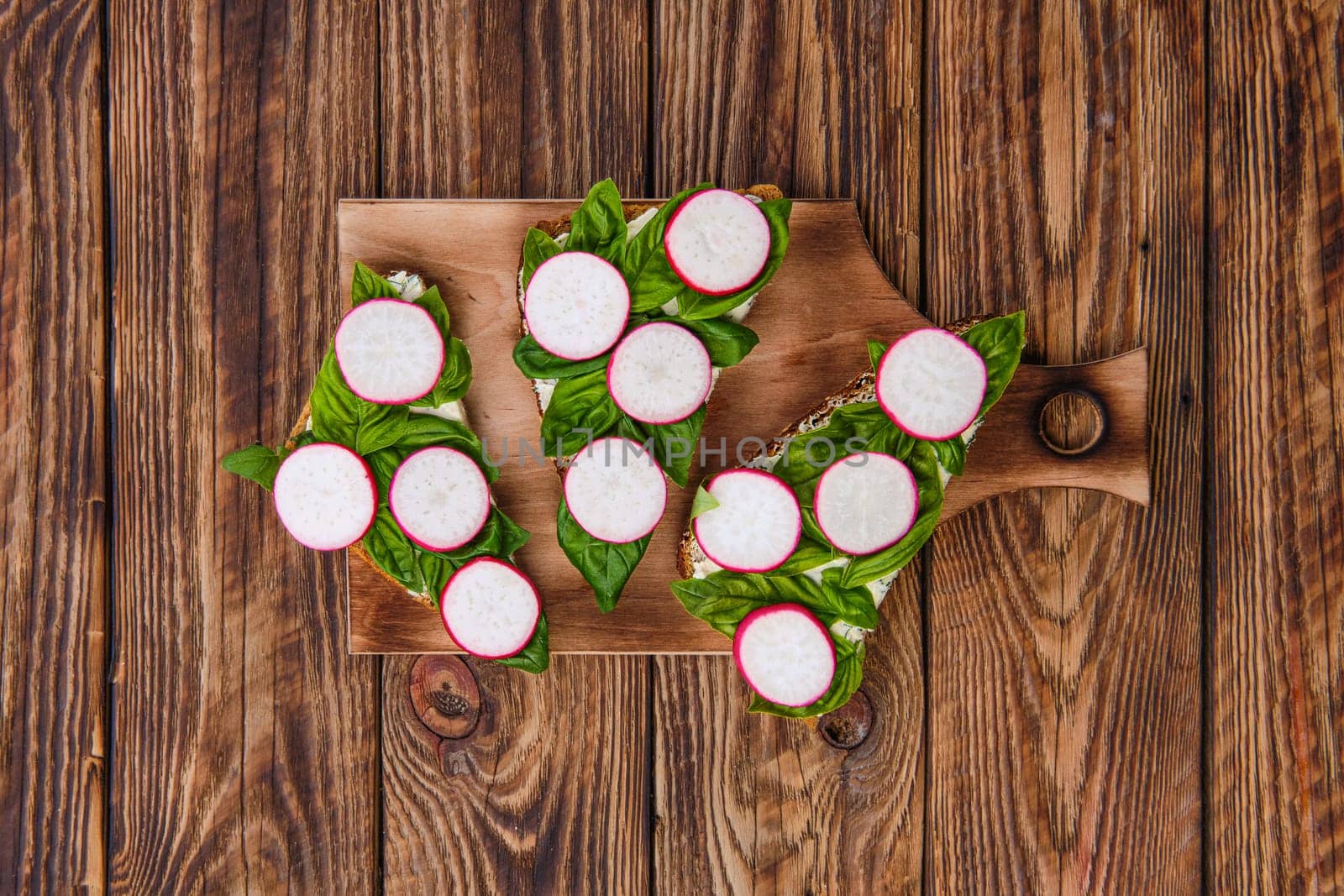 Top view of sandwiches with soft garlic cheese, basil and radish