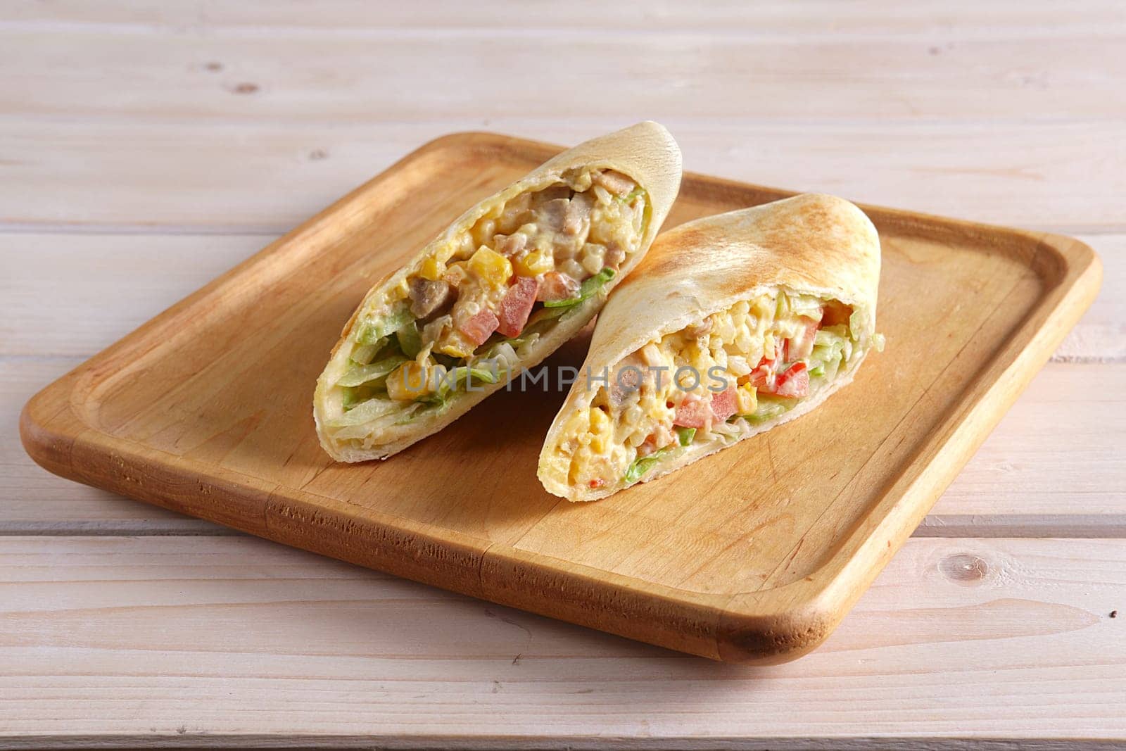 Burritos wraps with meat, beans and vegetables on wood board