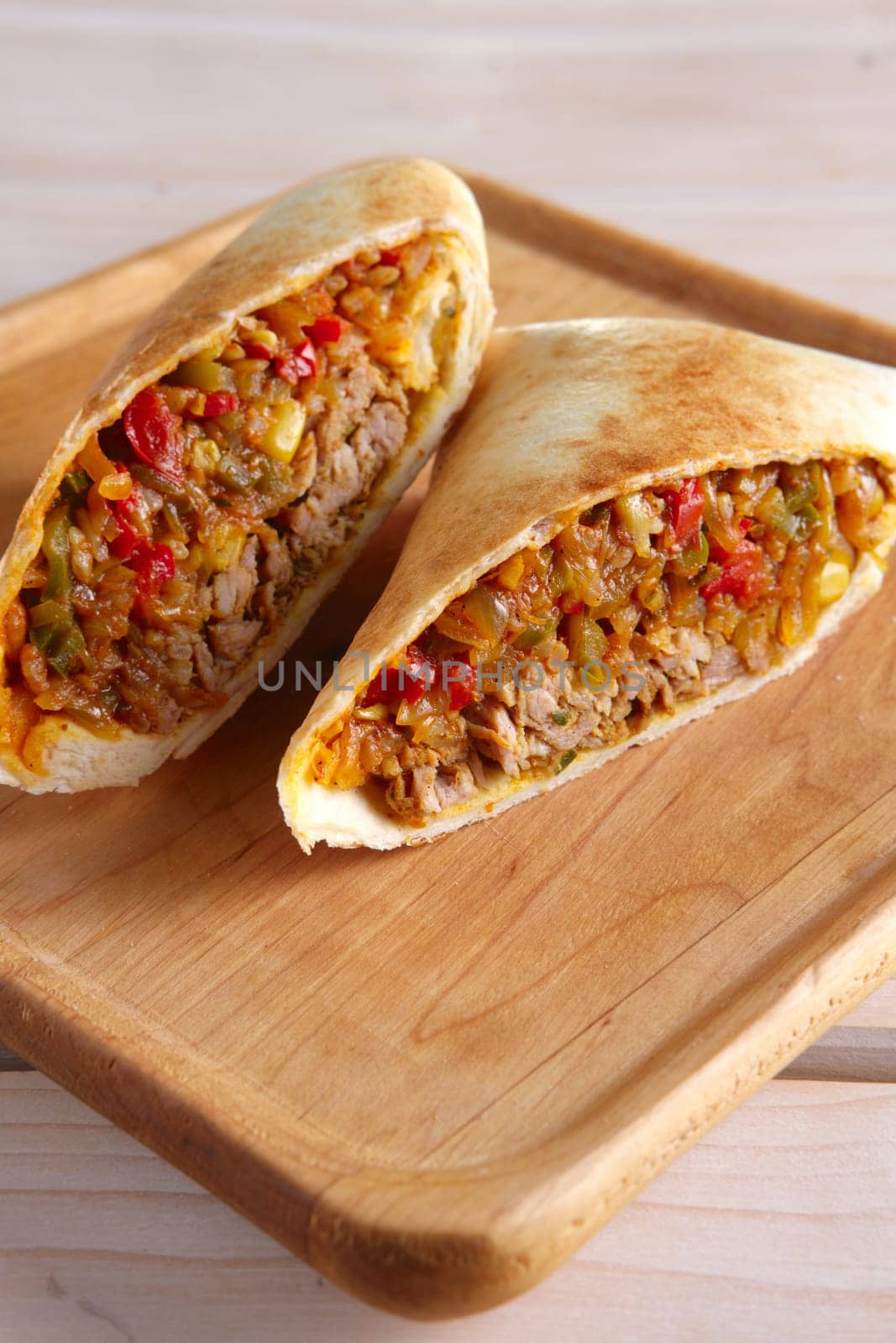 Burritos wraps with meat, beans and vegetables on wood board