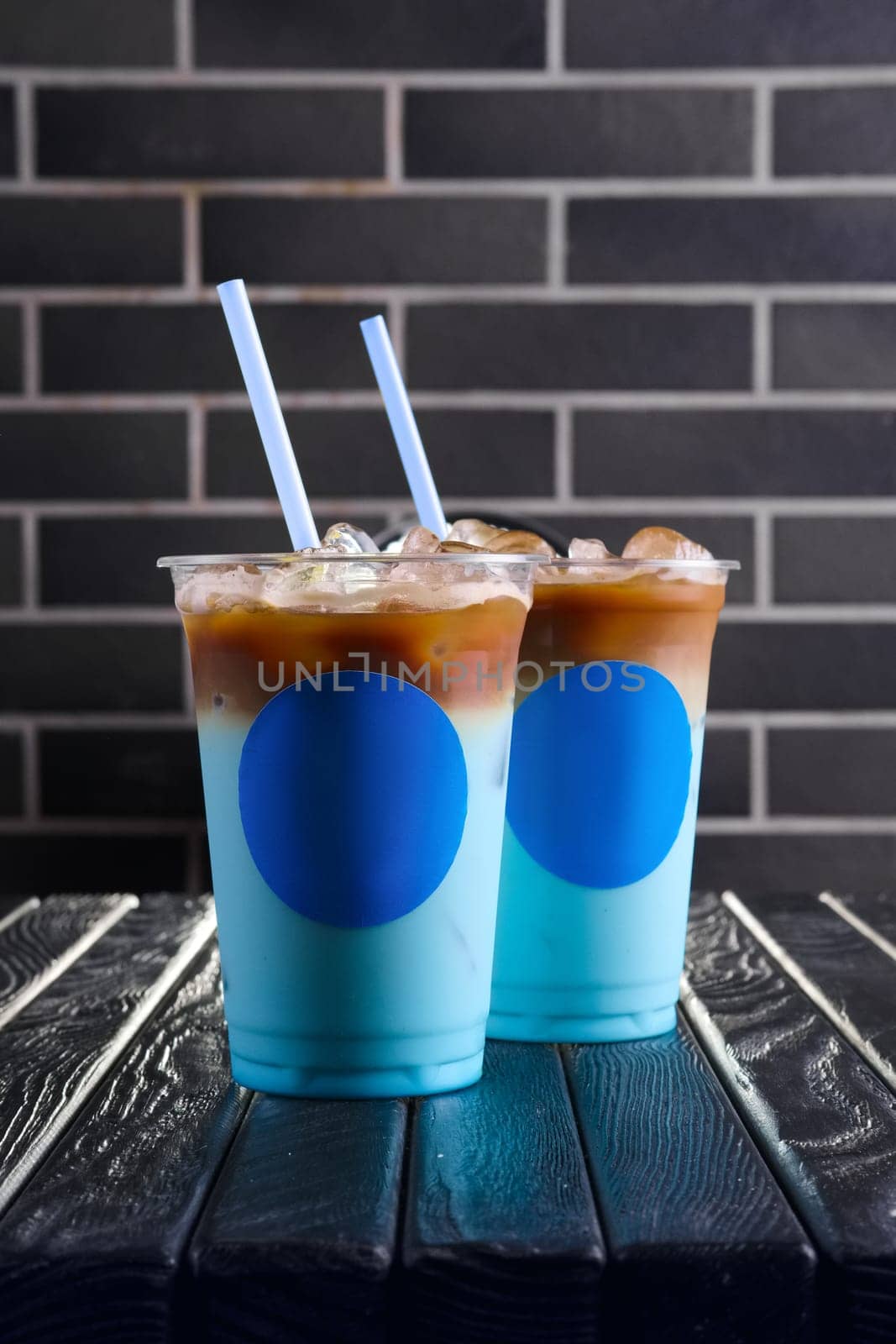 Concept of blue coffee cocktail. Plastic take away cup of blue ice drink.