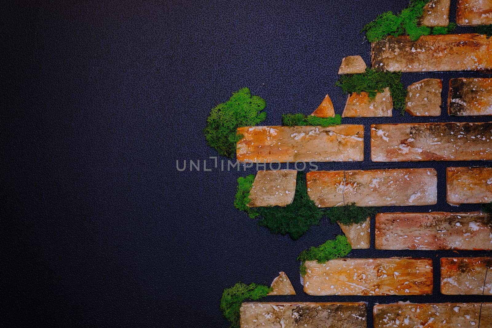 Black wall with bricks in the green moss and wooden clock and warm light. Place for text. Banner concept