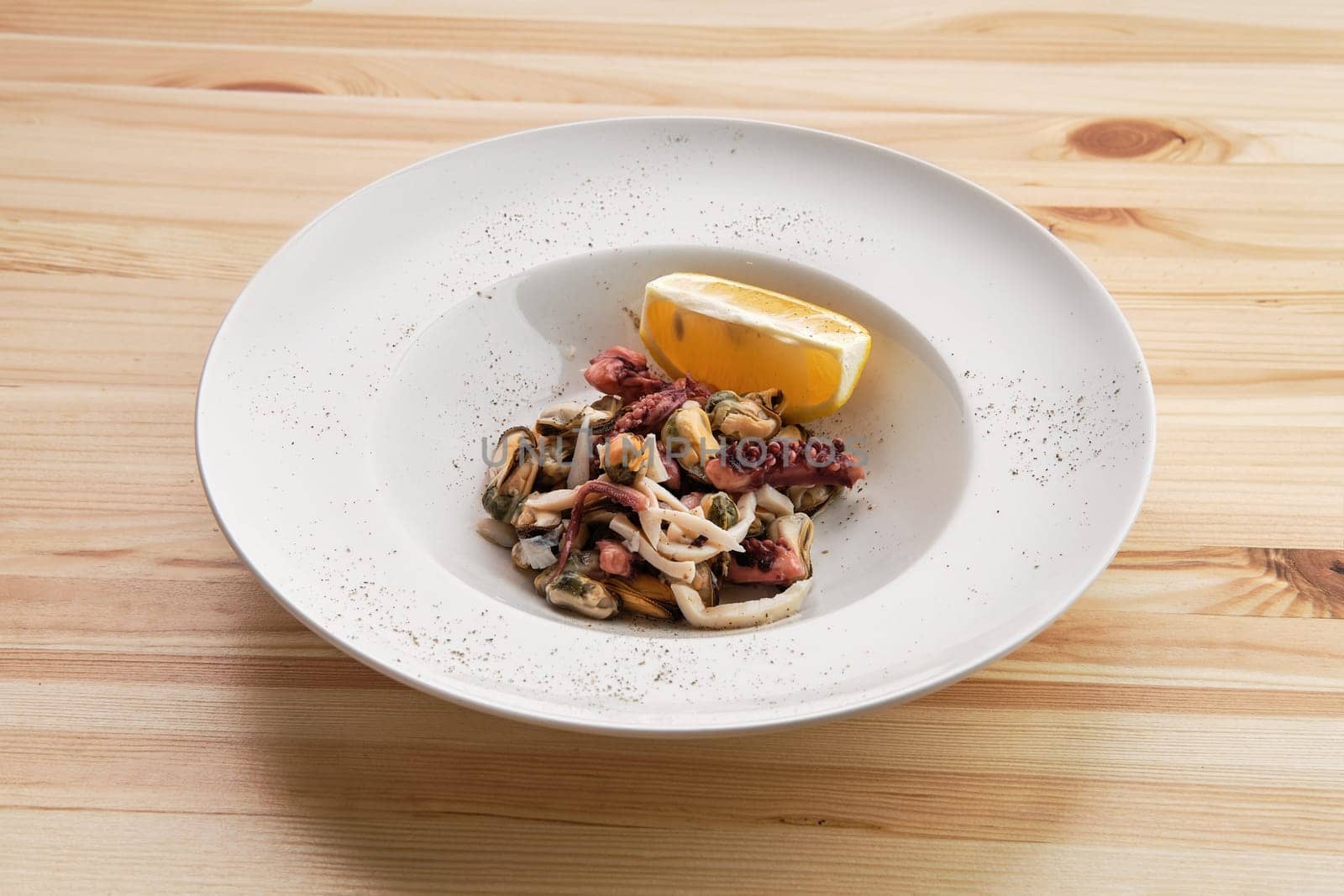 Salad with octopus, shrimps and mussels on wooden table