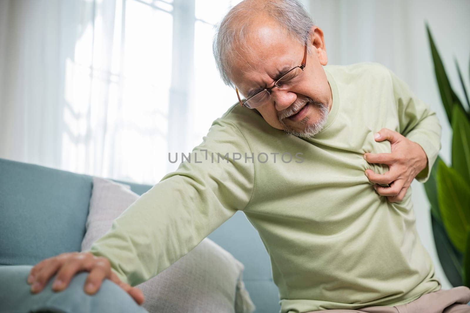 Asian older man have congenital disease suffering from heartache alone at home, Senior man bad pain hand touching chest having heart attack, Old age retirement health problems unhealthy diseased
