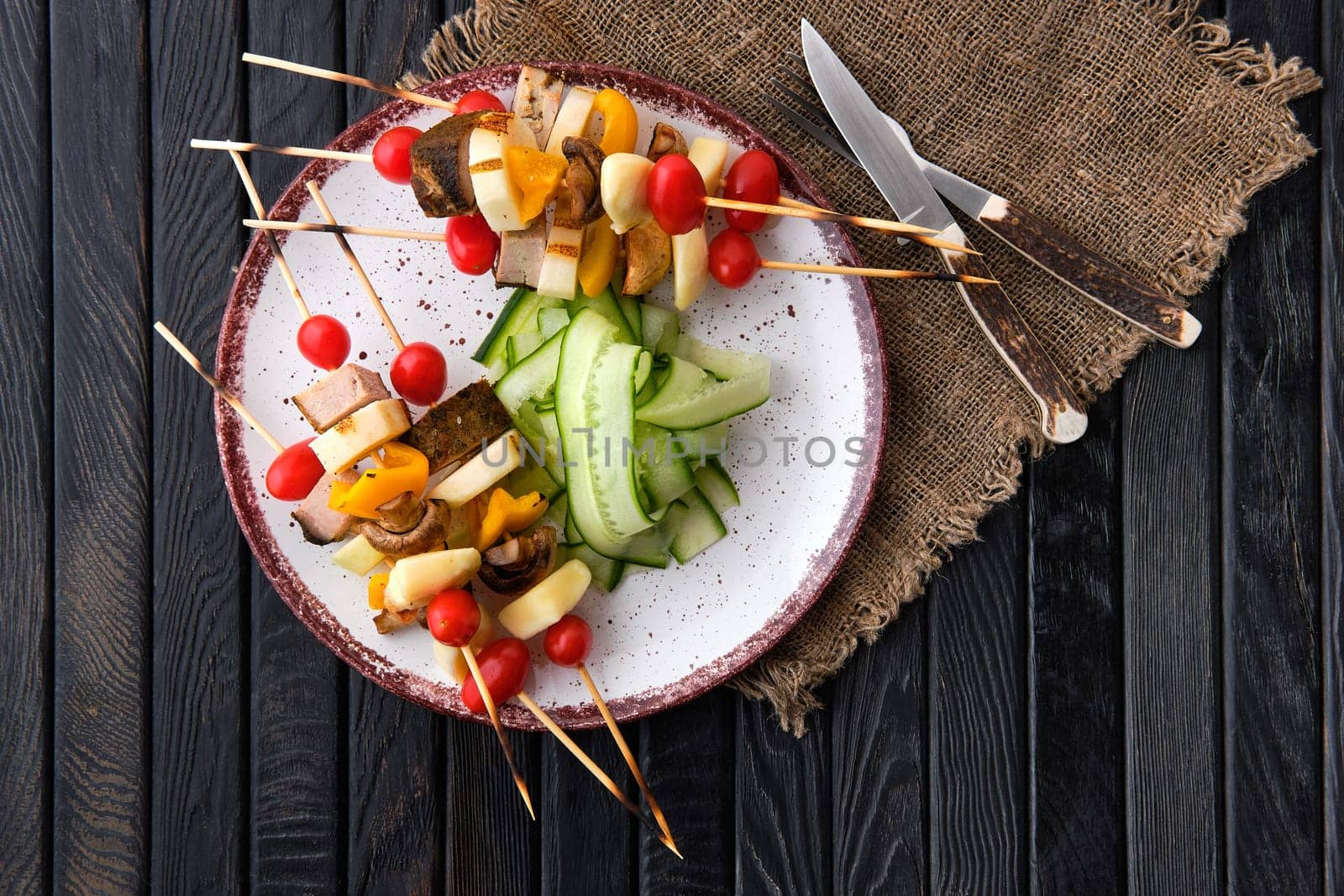 Shashlik with vegetables, mushrooms and mozzarella on dark wooden table