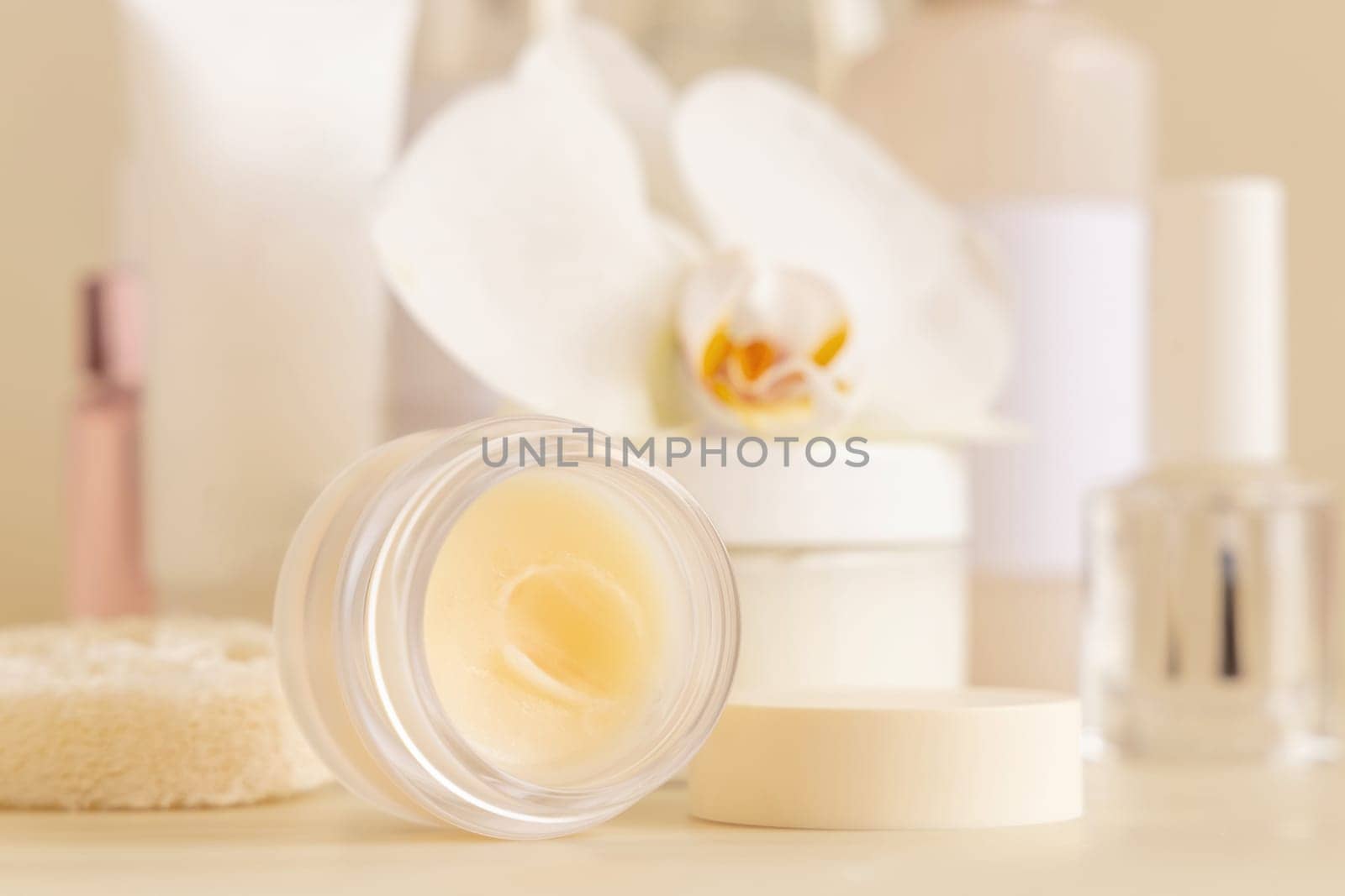 Smass opened Glass jar and other cosmetics near white orchid flower on light beige close up. Beauty products for everyday woman face care routine, Exotic Spa Treatments