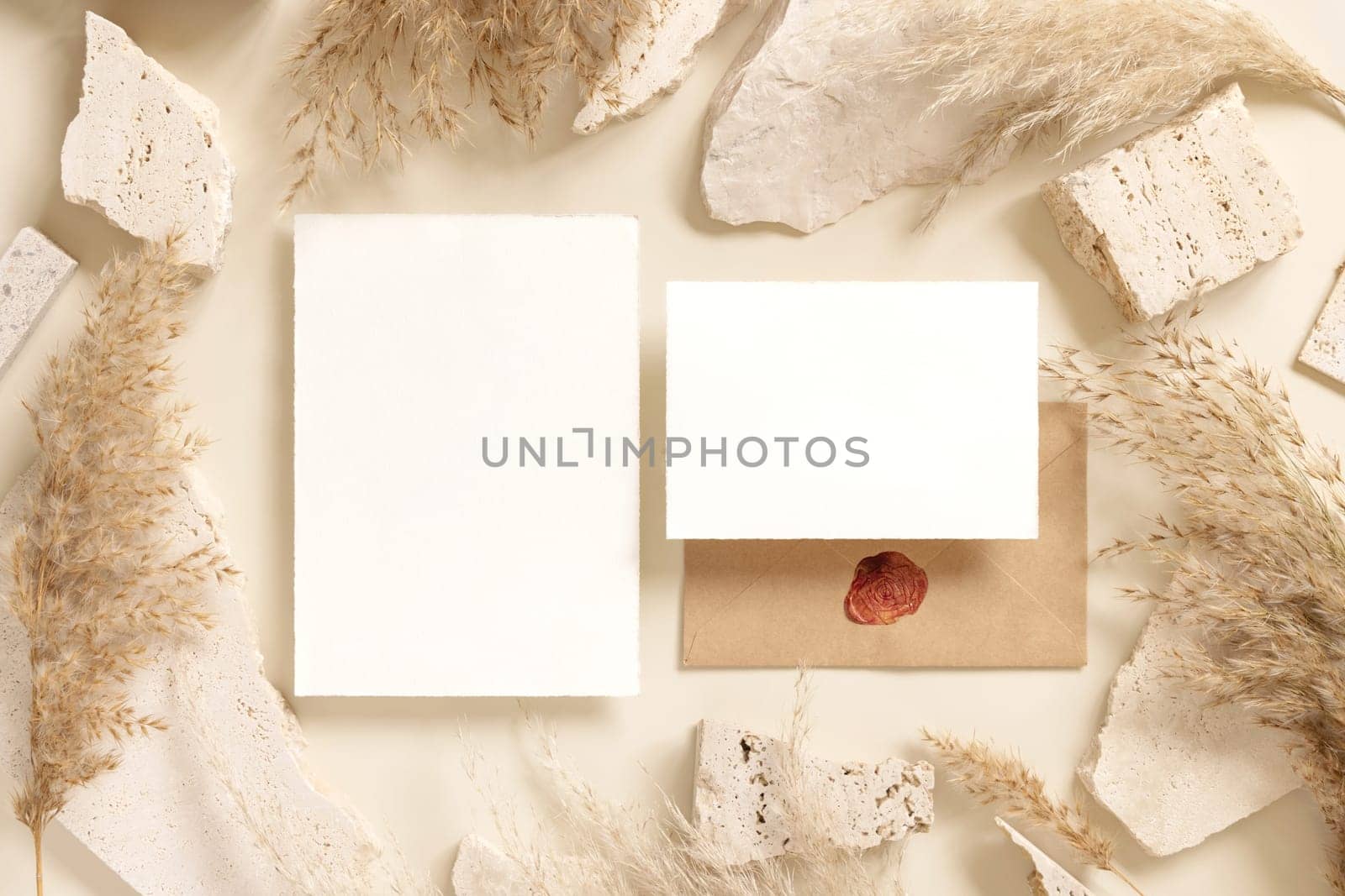 Blank cards near beige travertine stones and dried pampas grass top view, mockup. Boho scene. Bohemian or close to nature greeting or wedding Invitation. Close to nature.