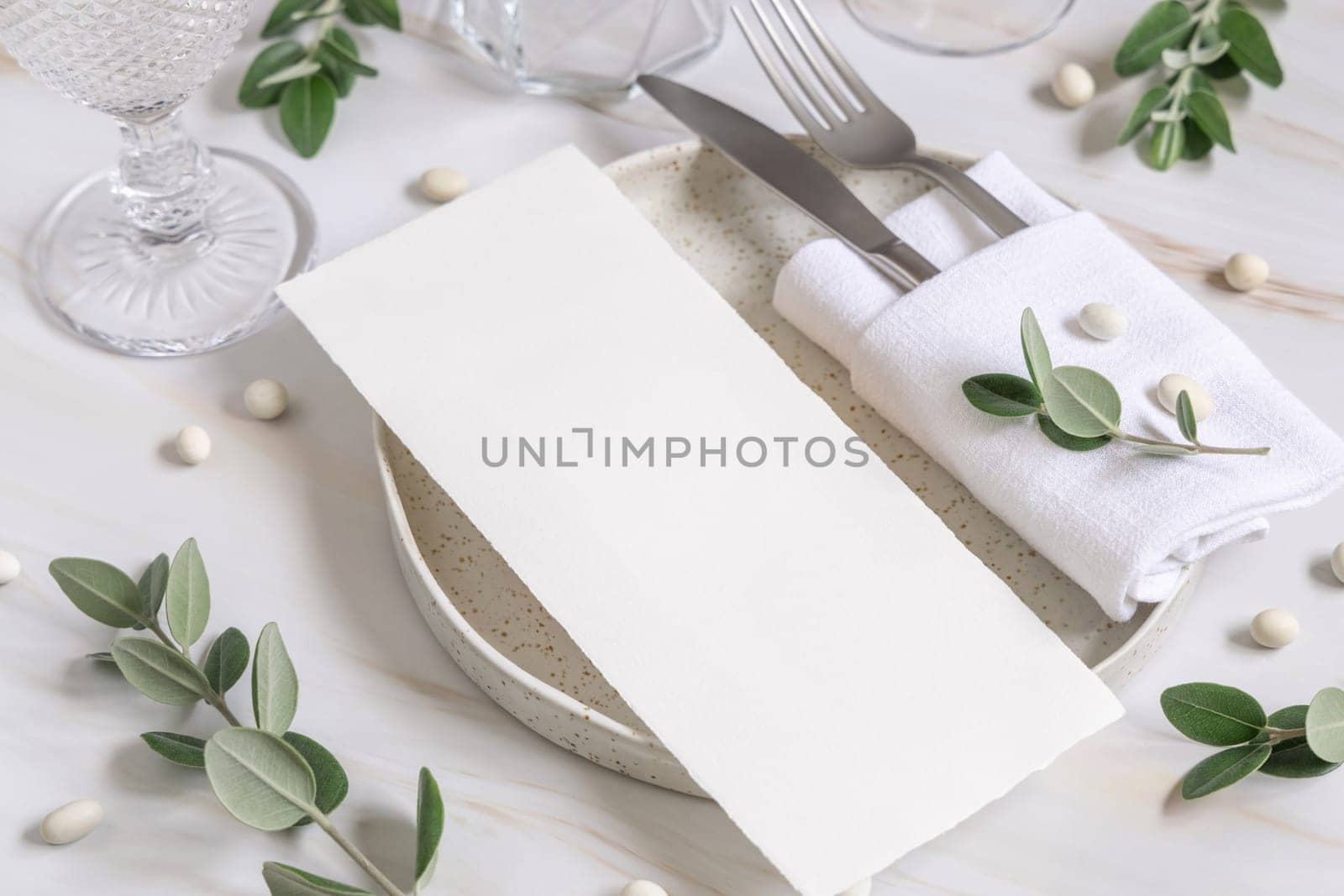 Elegant Table setting with a blank card decorated with eucalyptus branches close up, Wedding Mockup. Romantic table with paper menu card. Close to nature and simplicity concepts