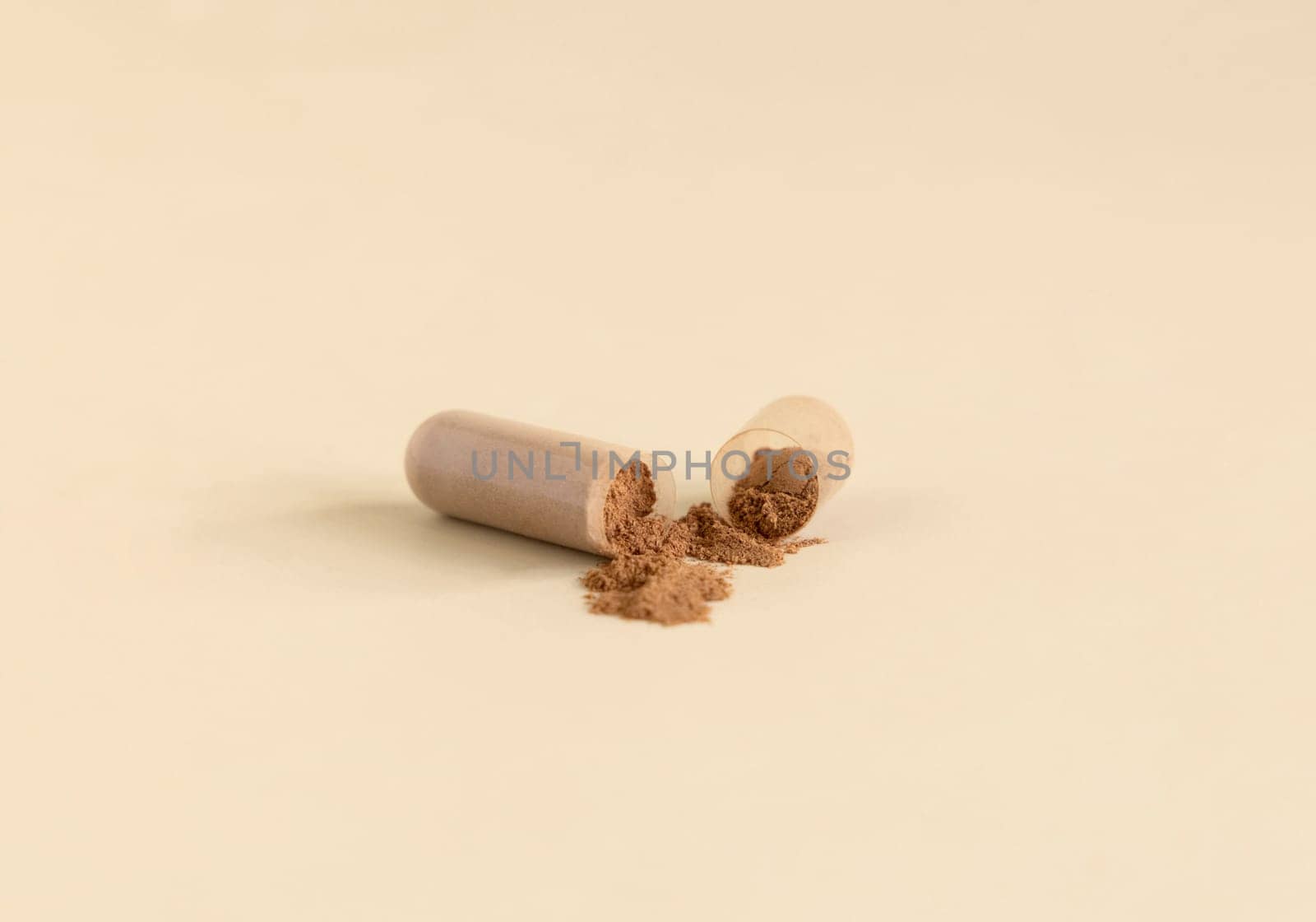 Medical capsule opened to show brown powder on light beige close up. Preventive medicine and healthcare, taking dietary supplements and vitamins. Pharmaceutical product