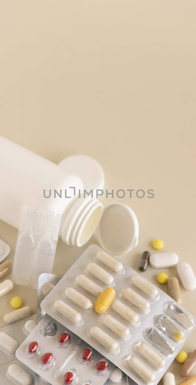 Mix of pills and capsules in a aluminum and plastic blisters with some missing pills already used on light beige close up, copy space. Preventive medicine and healthcare, dietary supplements