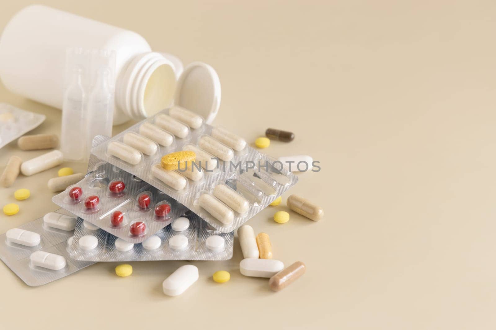 Mix of pills and capsules in a aluminum and plastic blisters with some missing pills already used on light beige close up, copy space. Preventive medicine and healthcare, dietary supplements