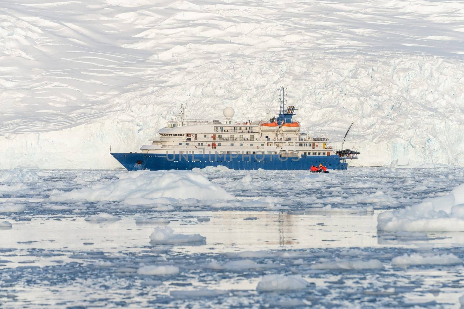 a Blue expedition ship in front of Antarctic iceberg landscape in Cierva Cove - a deep inlet on the west side of the Antarctic Peninsula, surrounded by dramatic glacier fronts