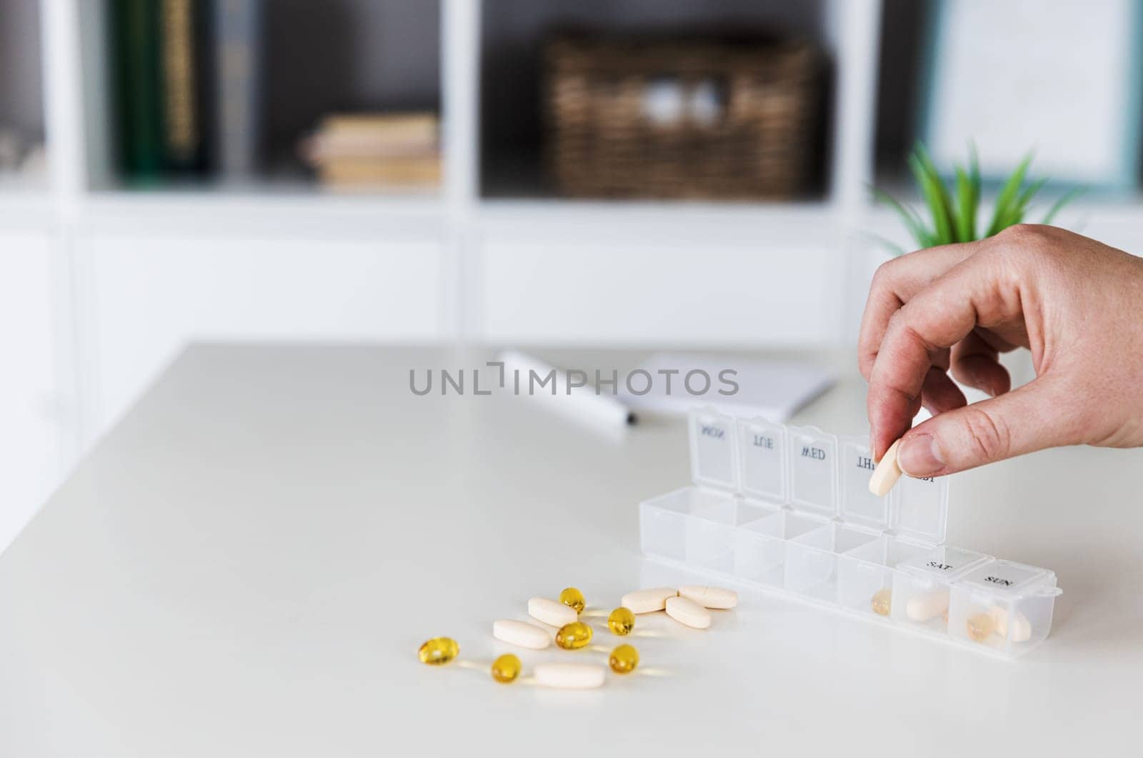 Closeup of female elderly hands sorting, organizing pills. Medical pill box with doses of tablets for daily take with white, yellow, beige drugs, capsules. Young woman get her daily vitamins at home