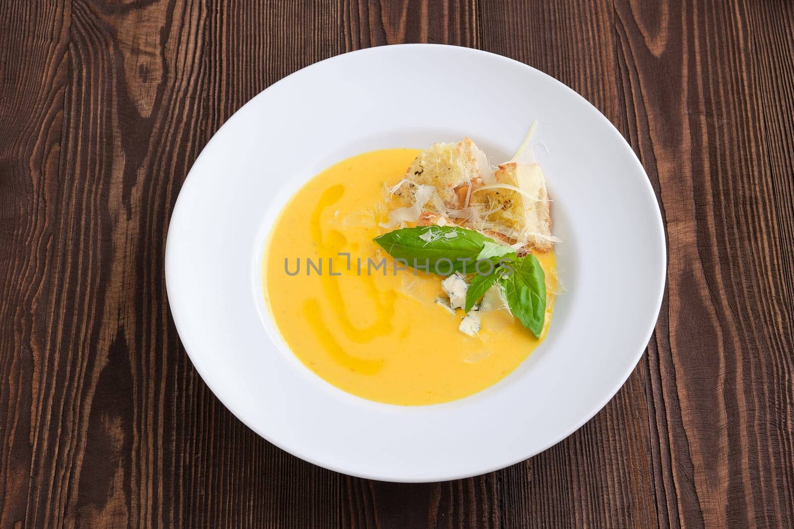 Top view of cheese soup with blue cheese and crouton on dark wooden background