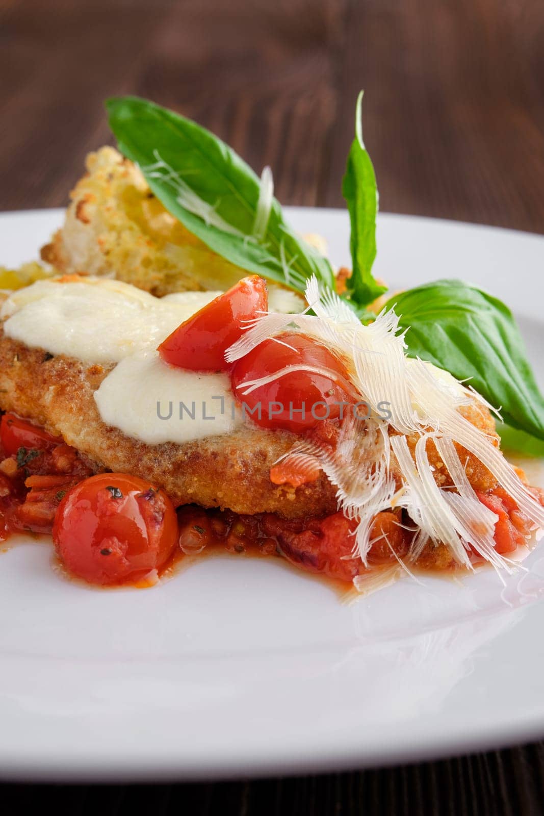 Soft focus photo of roasted chicken fillet with tomato cherry, parmesan and crouton on dark wooden background