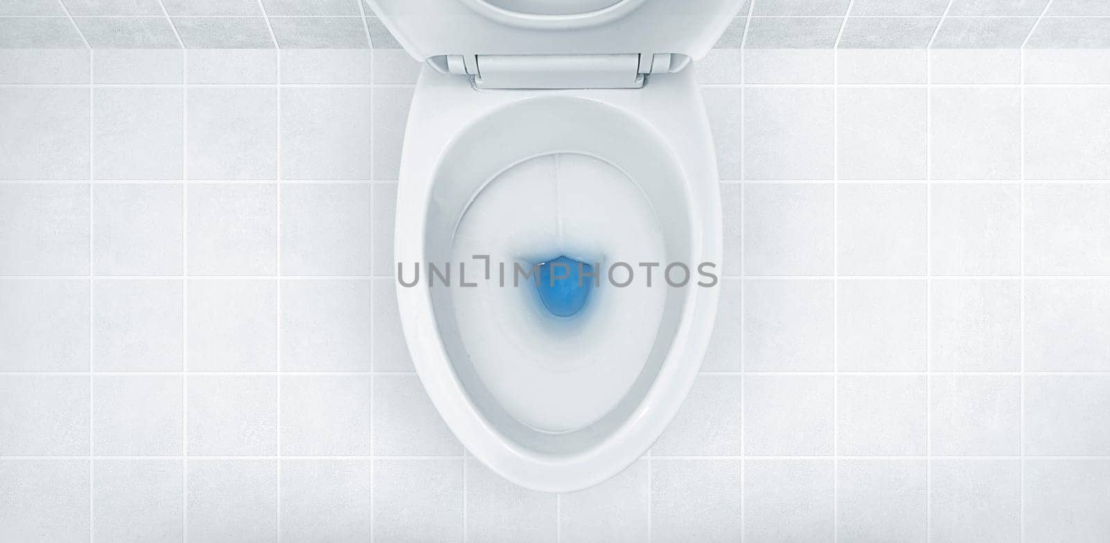 Top view of toilet bowl, blue detergent flushing in it