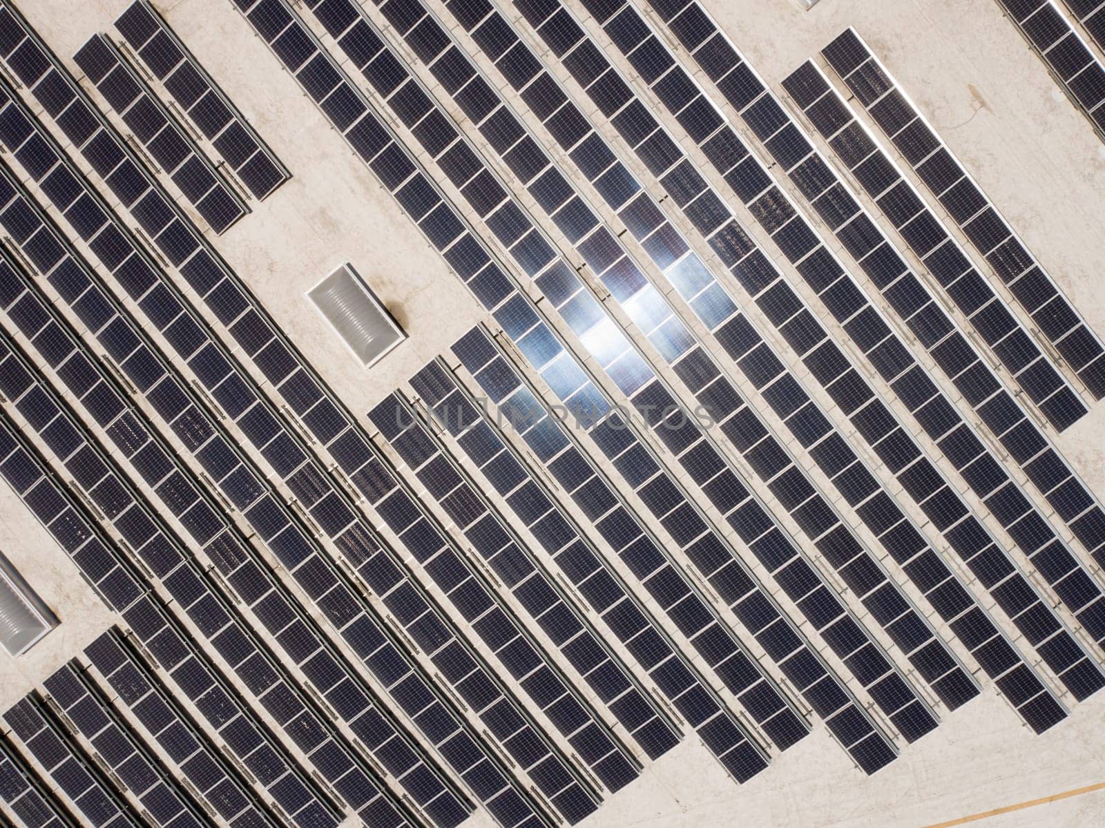 Aerial View of Solar Panels Mounted on Roof of Large Industrial Building or Warehouse.