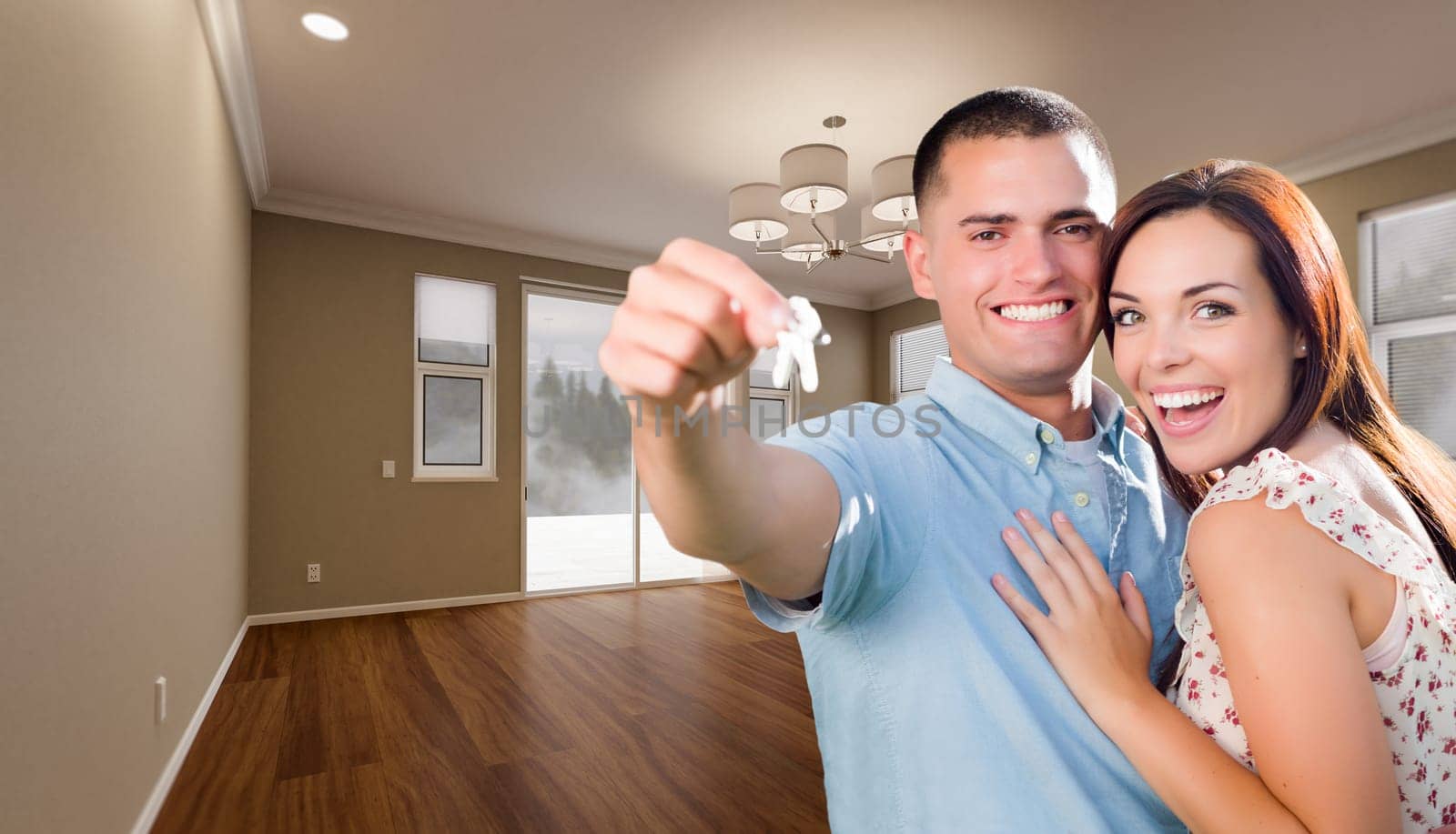 Young Military Couple with House Keys In Empty Room of New Home.