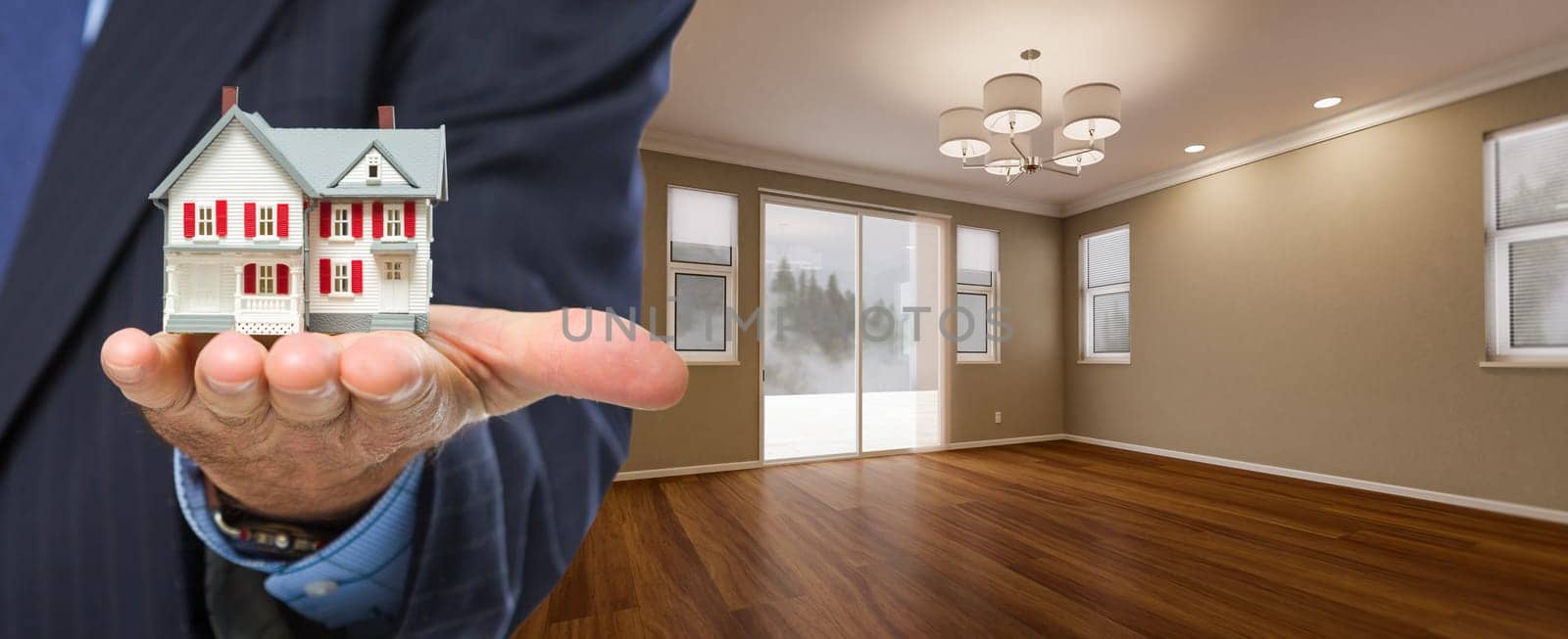 Real Estate Agent Holding Model Home In New Room of House.