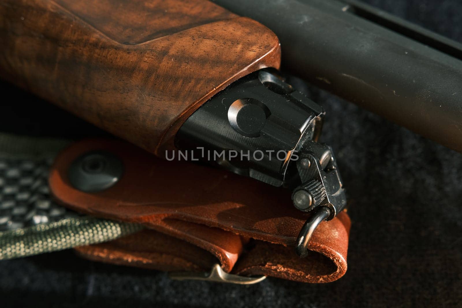 shell magazine into the barrel of a long shotgun on dark background with leather belt.