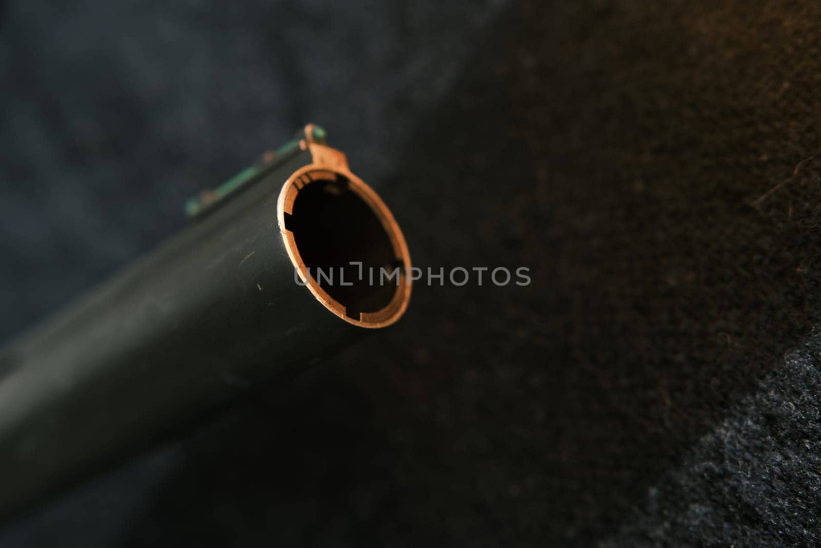 Muzzle of shotguns. Shotgun - macro shooting. Muzzle end of the barrel with green bead on the end on a black cloth background.