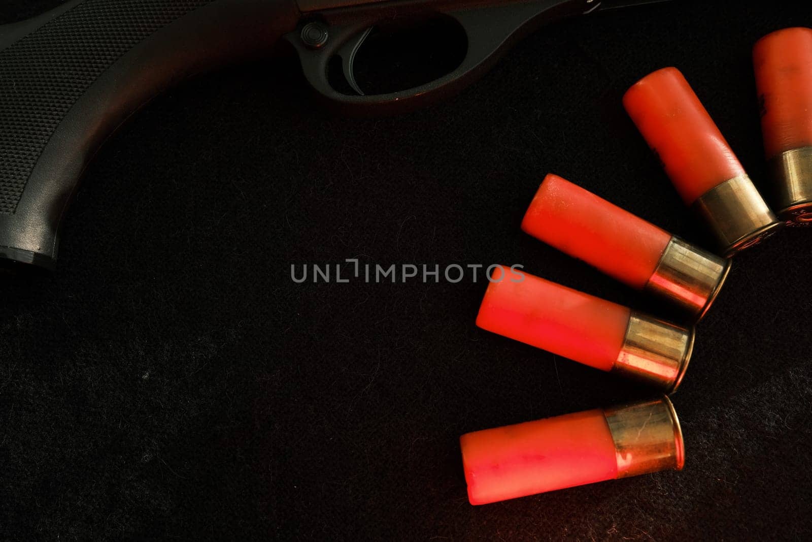Trigger of a rifle on black background with red lightning with Shotgun shells on a black surface. Ammunition for 12 gauge smoothbore weapons. Hunting ammunition. Dark background