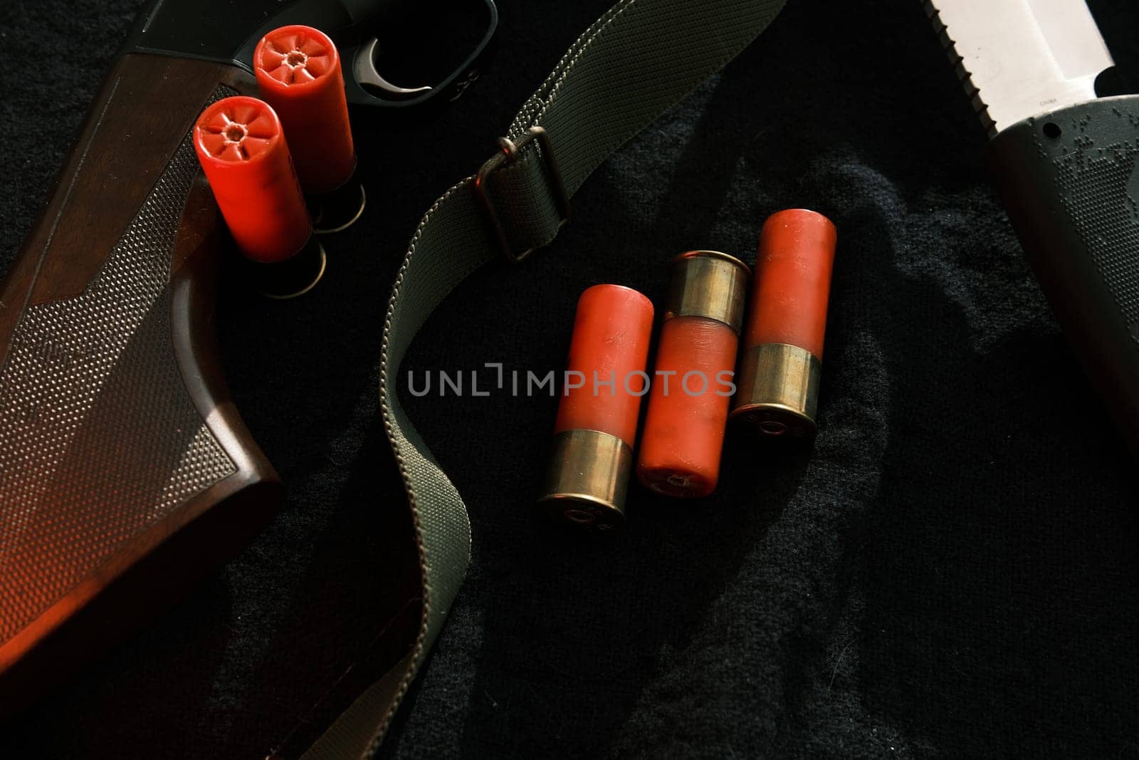 Weapon on black cloth: knife, rifle, shells,top view. Top view of knife, rifle shells