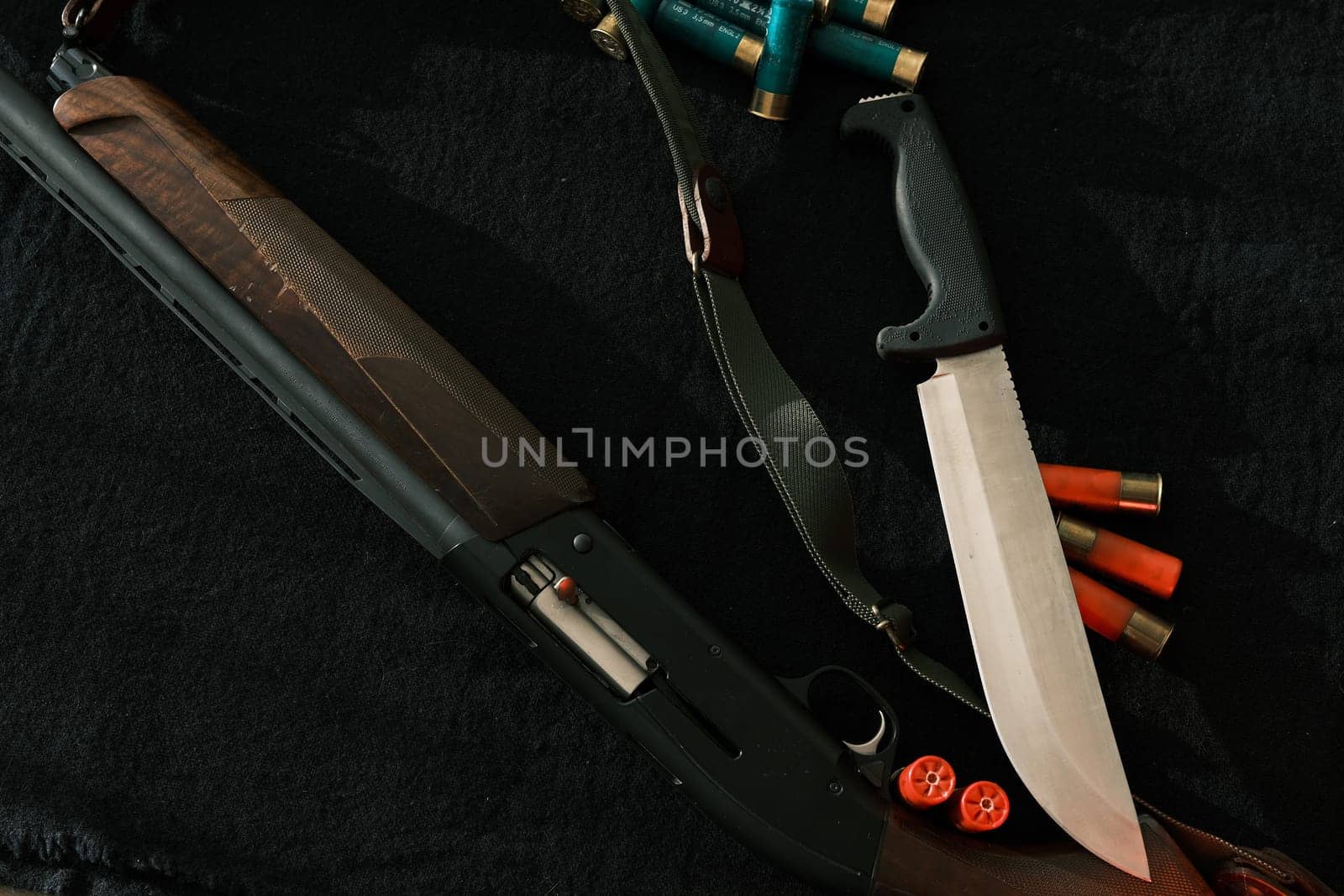 Weapon on black cloth: knife, rifle, shells,top view. Top view of knife, rifle shells