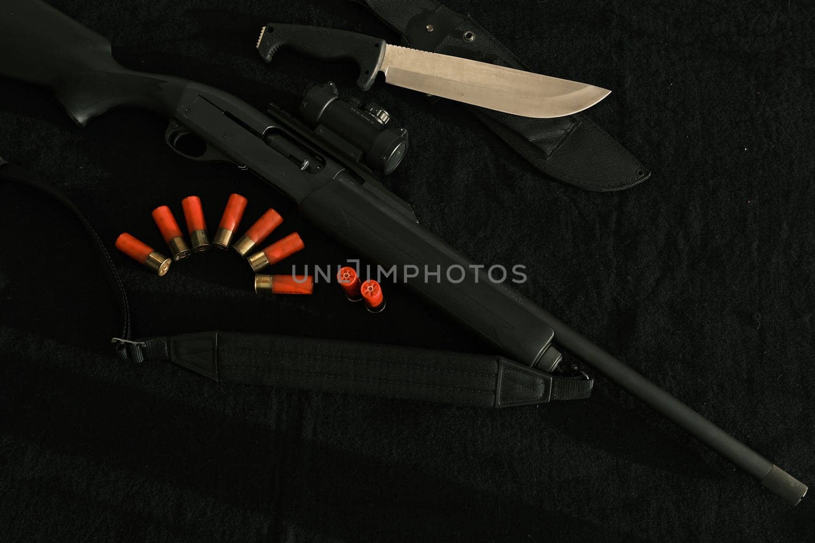 Weapon on black cloth: knife, rifle, shells,top view. Top view of knife, rifle shells